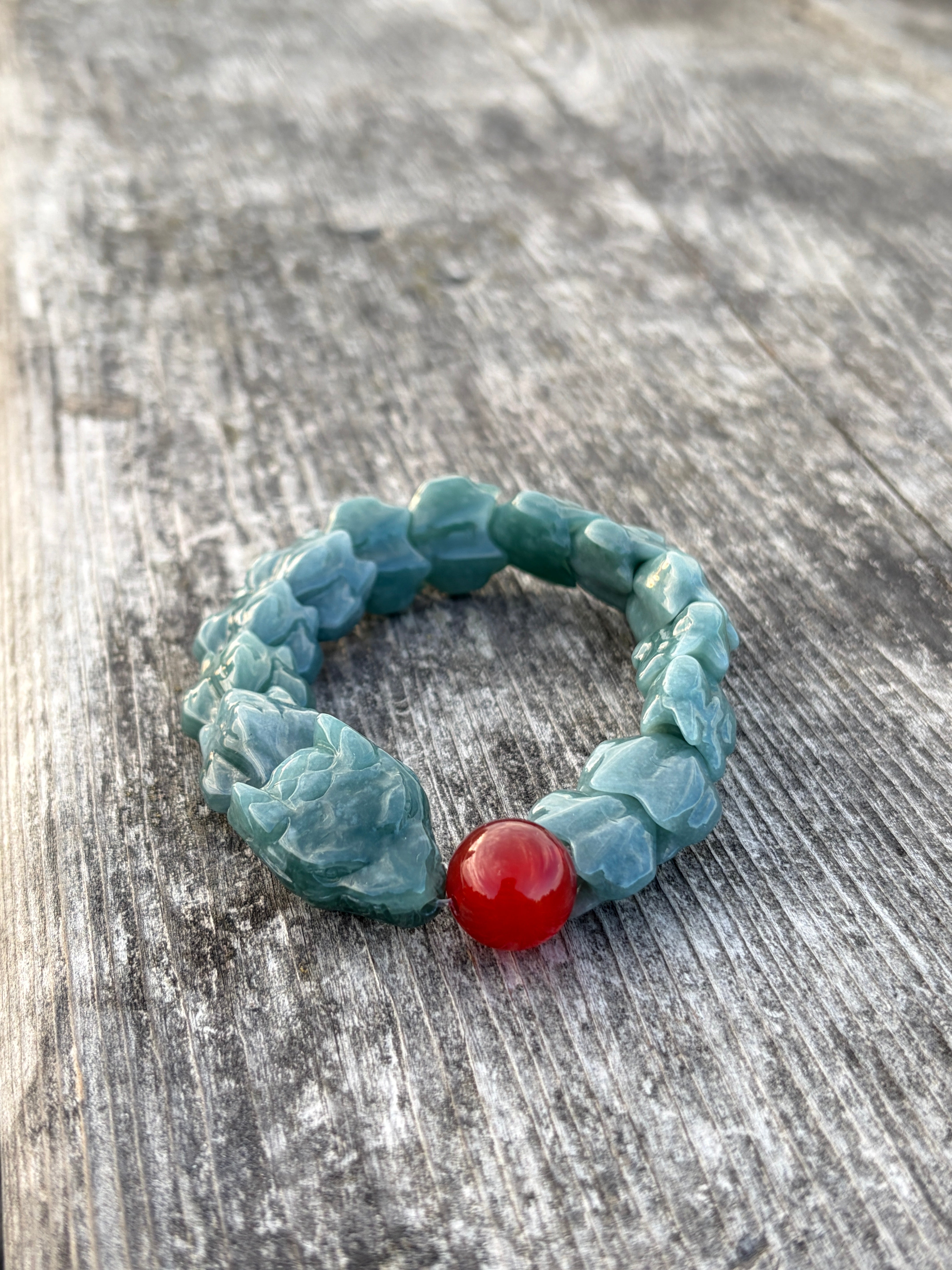 Carved green jadeite dragon bracelet with a red accent bead