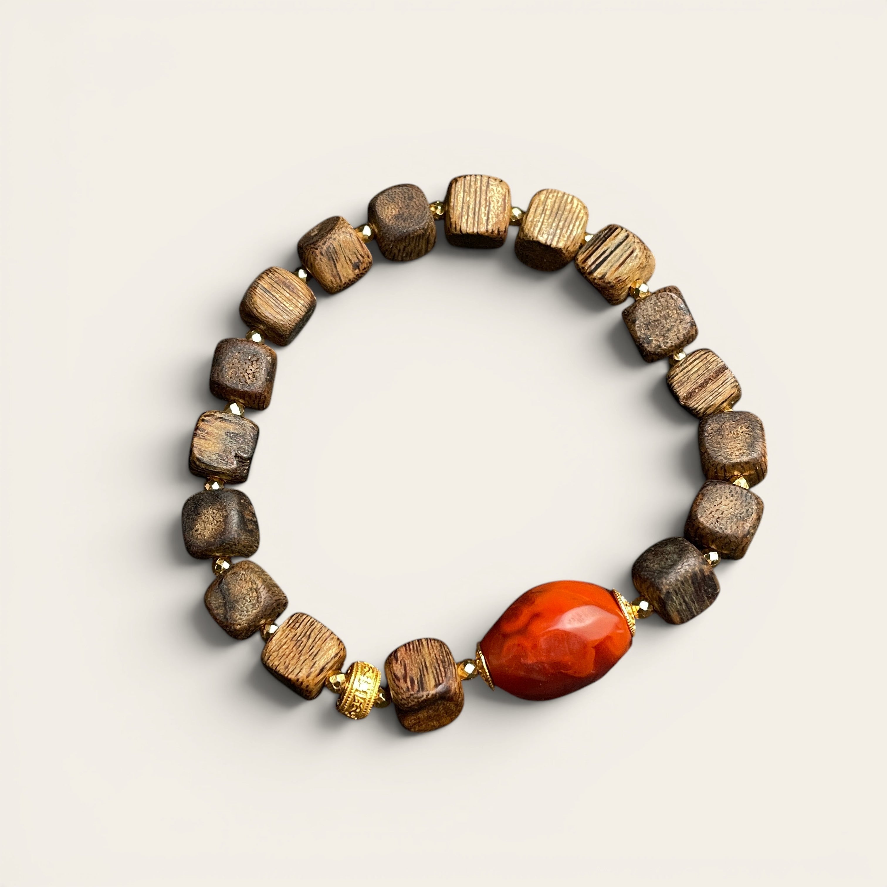 Sylvia Jewelry agarwood cubic block bracelet with a central red Nanhong agate barrel bead and gold-plated spacers.