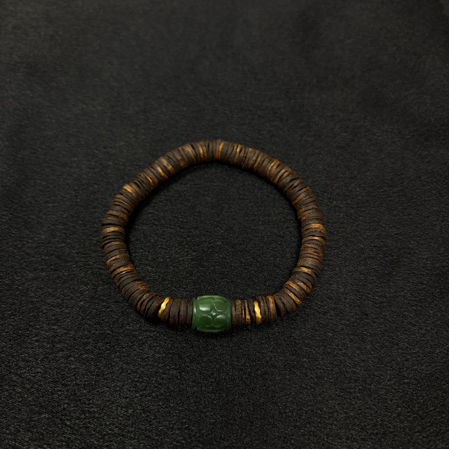 Sylvia Jewelry Rooted Spirit bracelet featuring dark agarwood beads, a carved green jade cylinder, and gold-tone accents.