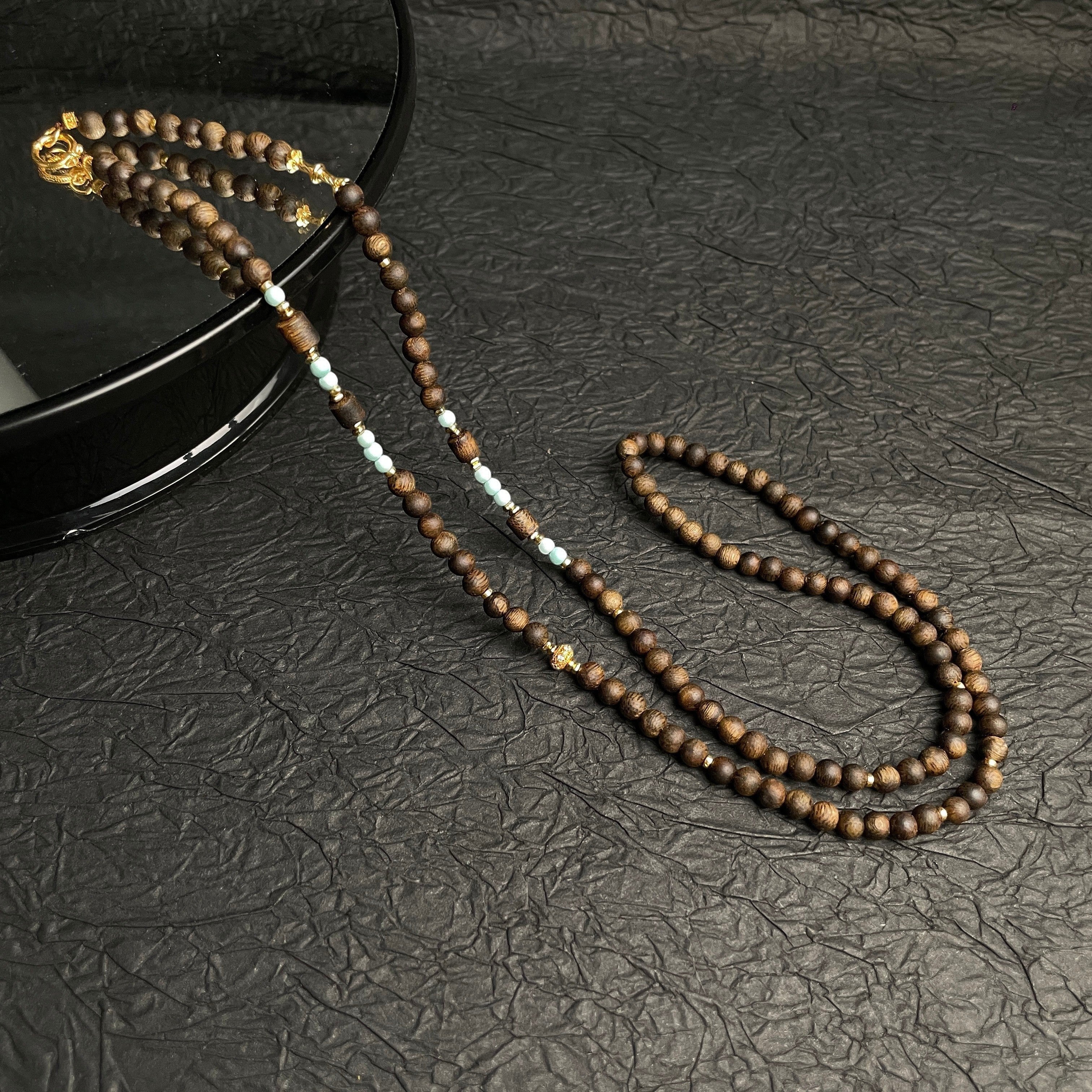 Sylvia Jewelry long necklace featuring natural agarwood beads, high-porcelain turquoise accents, and gold hardware.