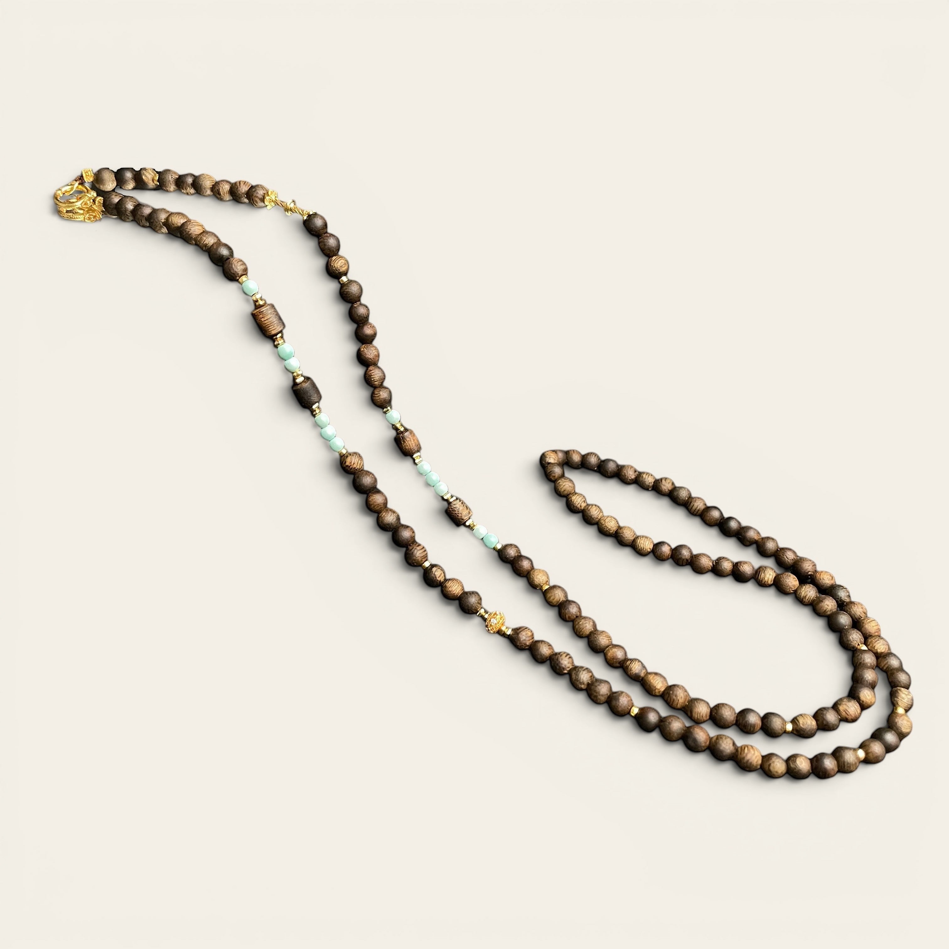 Sylvia Jewelry long necklace featuring natural agarwood beads, mint-green turquoise accents, and gold-plated filigree hardware.