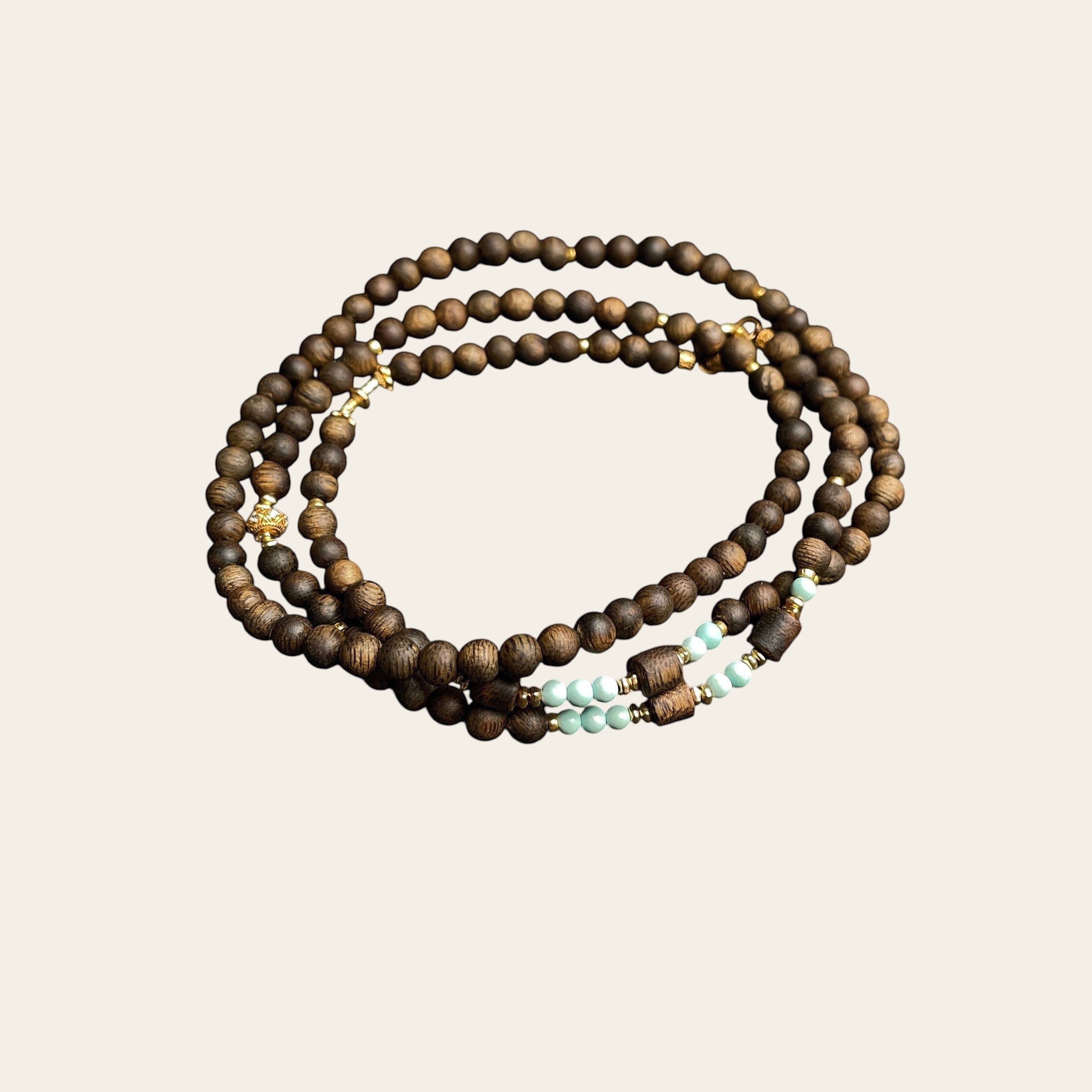 Sylvia Jewelry long necklace featuring natural agarwood beads, mint-green turquoise accents, and gold-plated hardware.