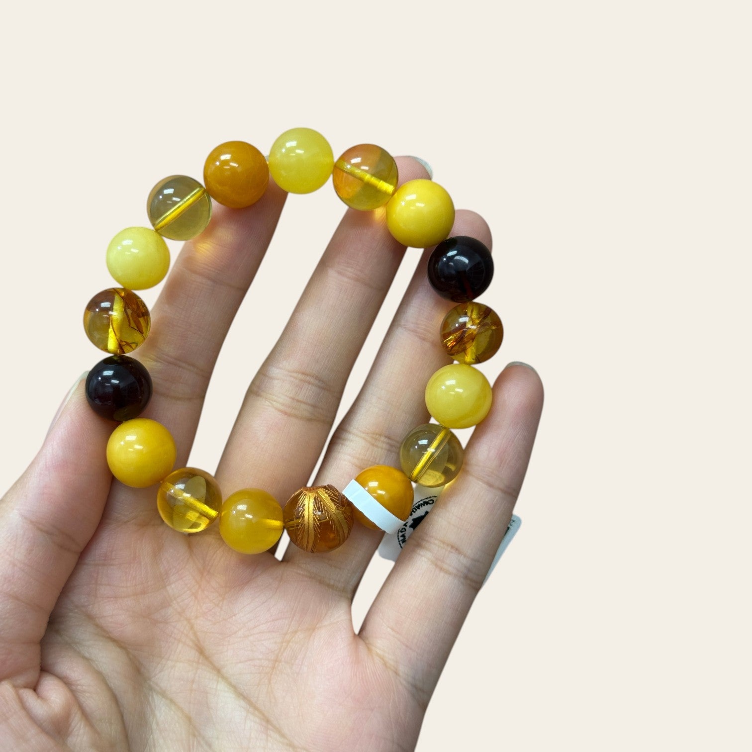 Sylvia Jewelry multi-variety Baltic amber and beeswax stretch bracelet with a hand-carved focal bead on a hand.
