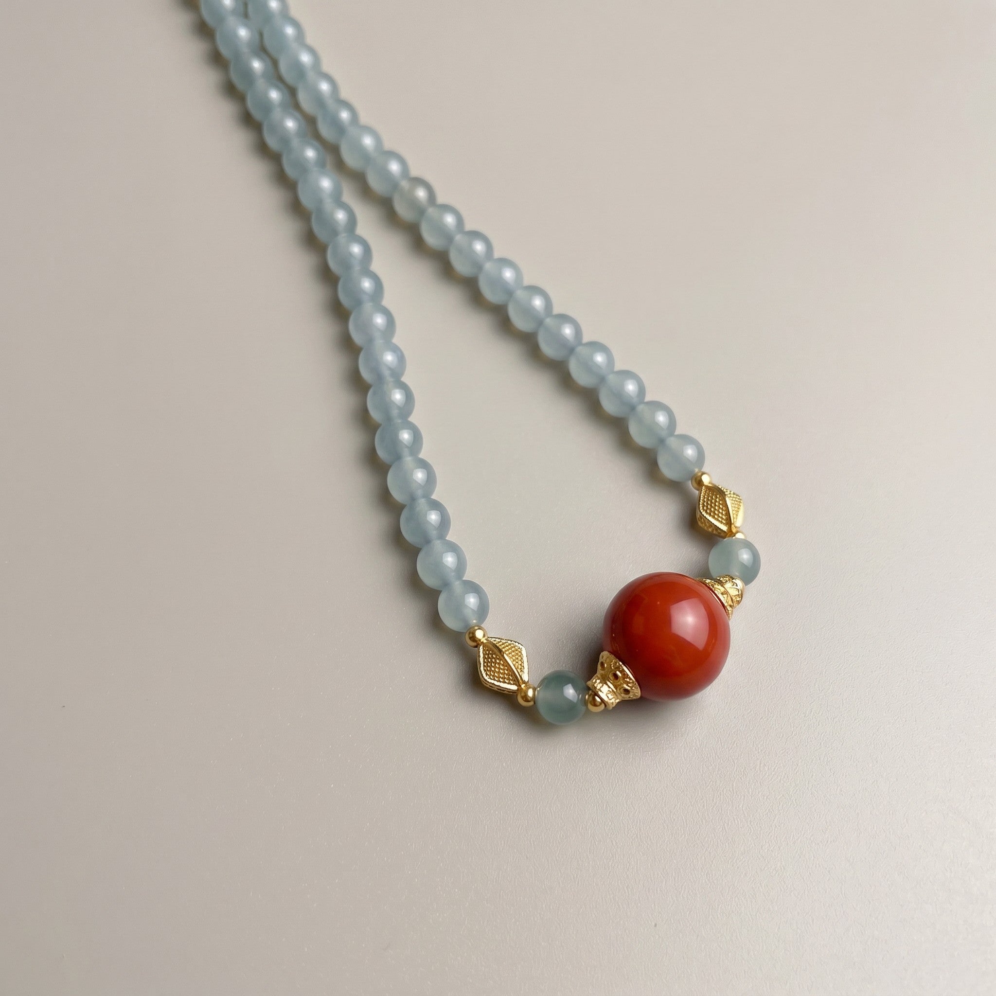 Sylvia Jewelry 浅蓝色串珠项链,镶嵌一颗醒目的橙红色圆形宝石,搭配金色菱形隔珠。