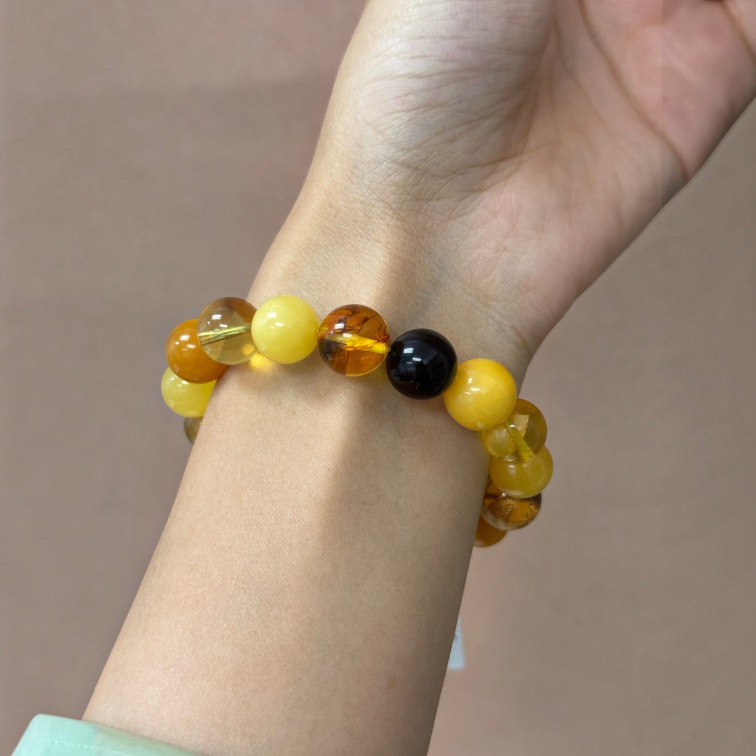 Sylvia Jewelry multi-variety Baltic amber and beeswax stretch bracelet with polished beads on a wrist.