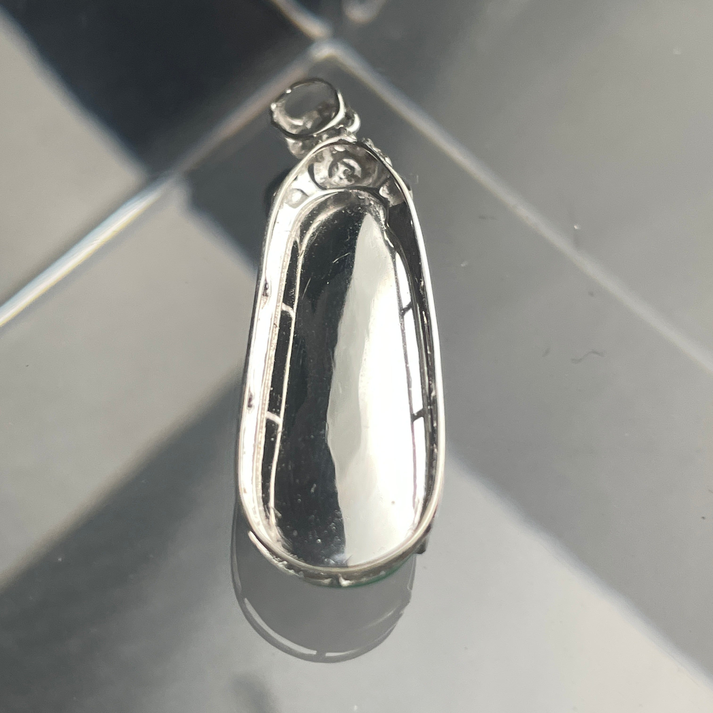Sylvia Jewelry 18K gold green jadeite bean pendant with a floral diamond-accented bail on a reflective surface.