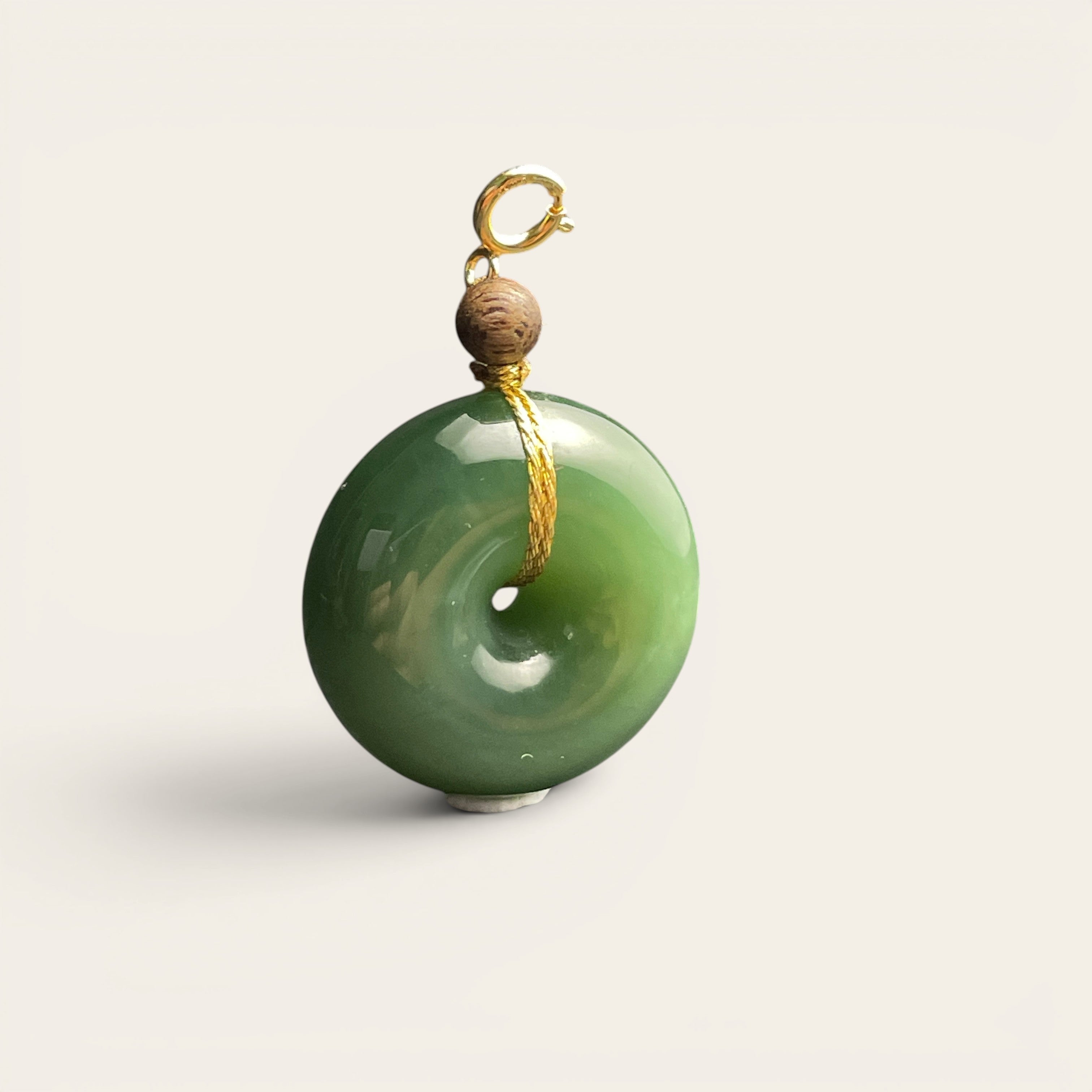 Sylvia Jewelry green jade donut pendant with a small wooden bead and gold clasp on a black display box