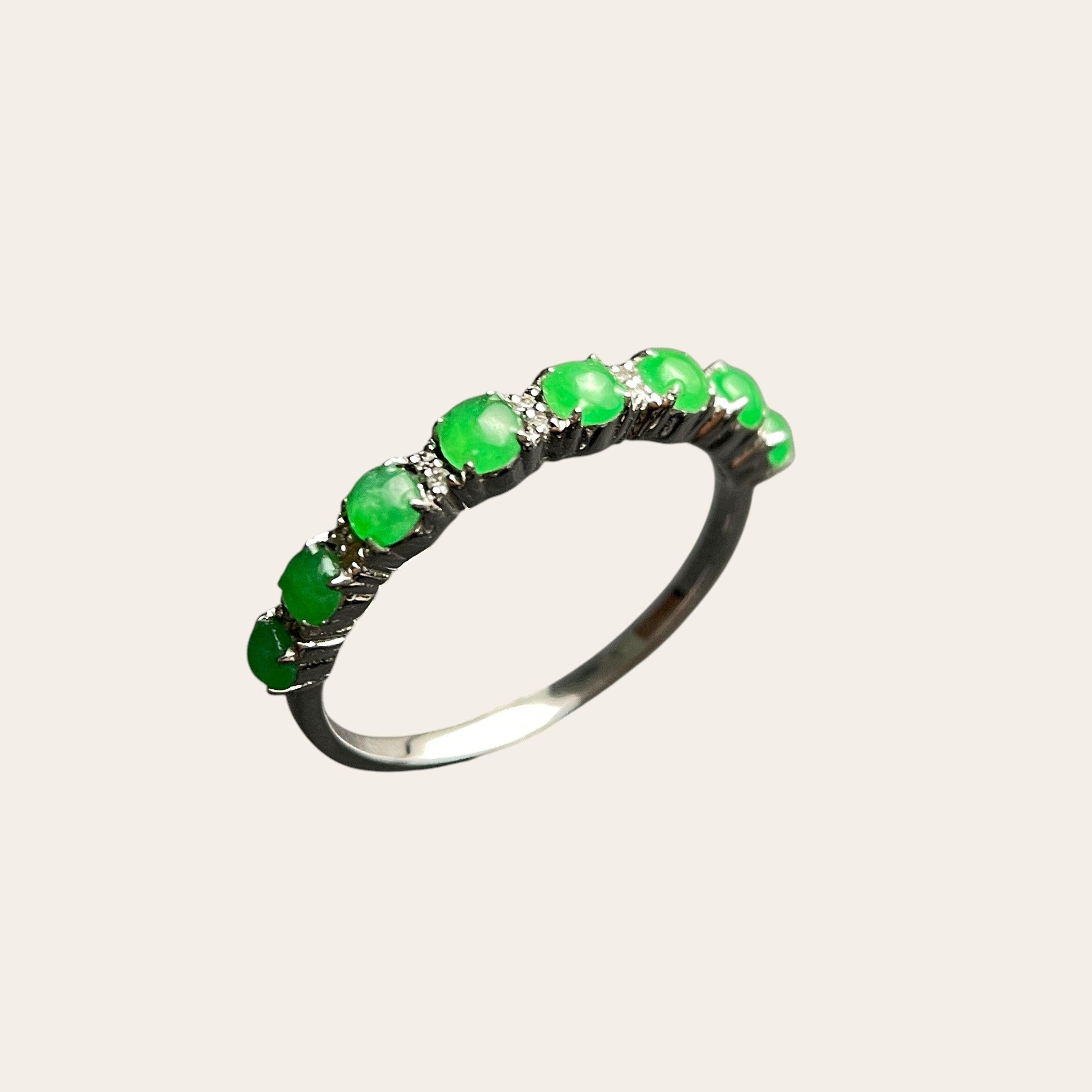 Sylvia Jewelry sterling silver ring featuring a row of vibrant green jade cabochon stones on a dark textured surface.