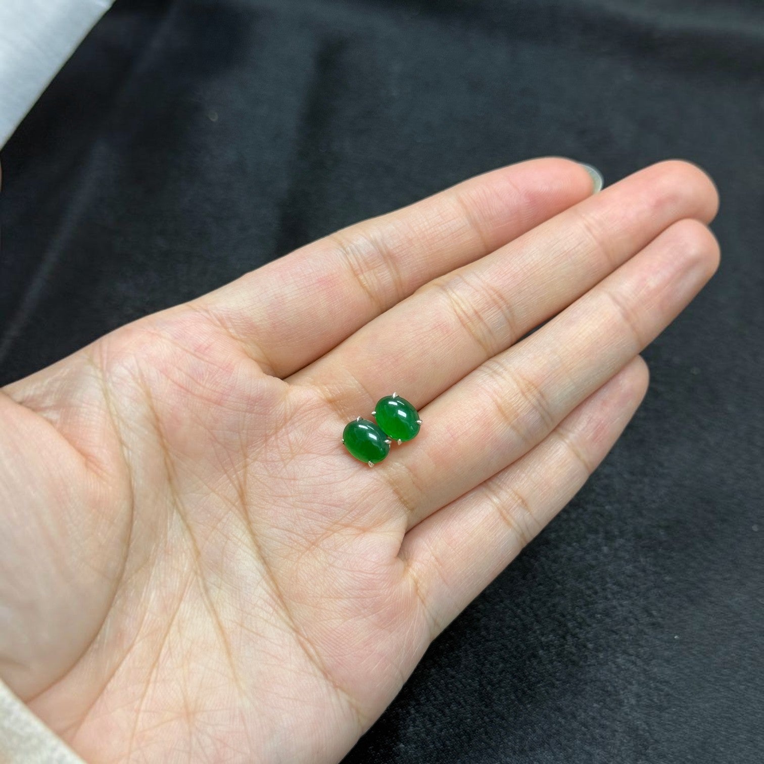 Sylvia Jewelry apple green jadeite stud earrings with S925 sterling silver prongs held in a palm.
