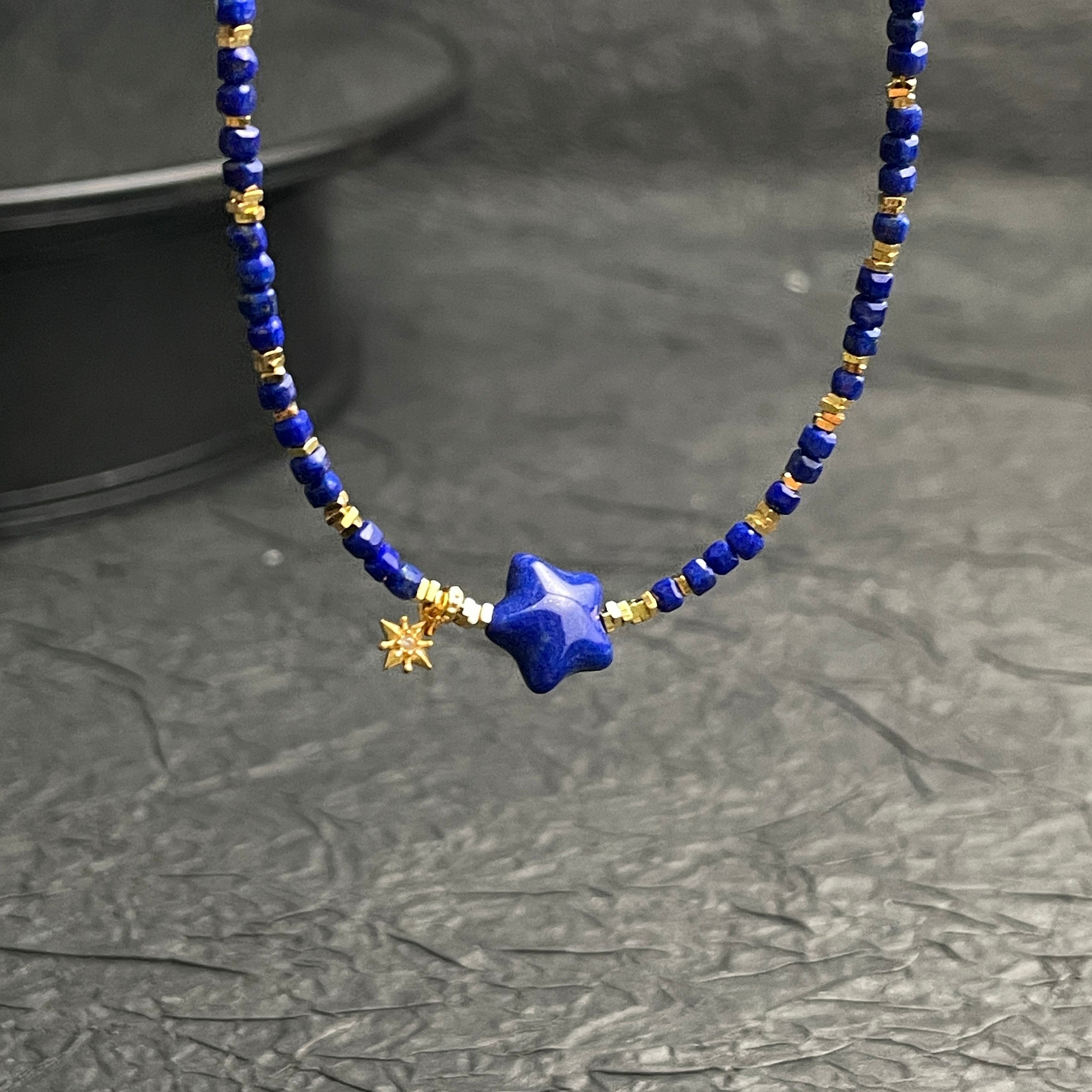 Sylvia Jewelry lapis lazuli beaded choker with gold-plated star pendant and dangling charm on a dark background.
