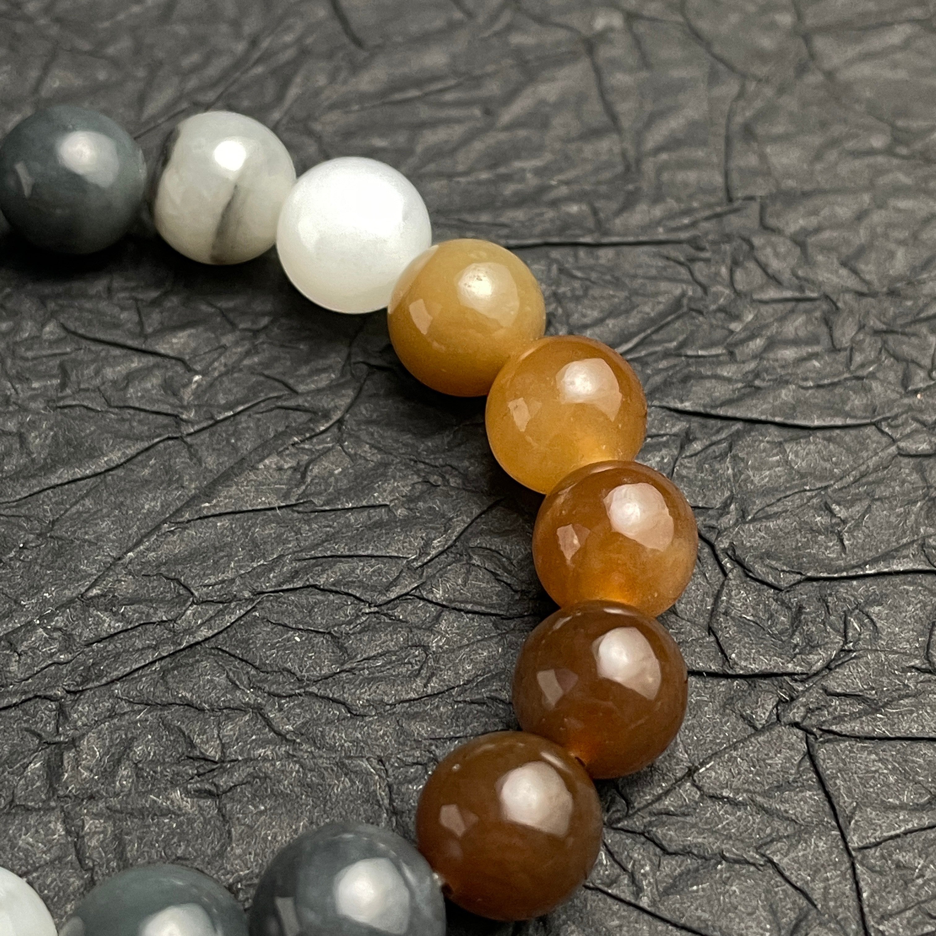 Sylvia Jewelry multi-colored Hetian nephrite jade bracelet with smooth, polished beads in amber, white, and grey tones.