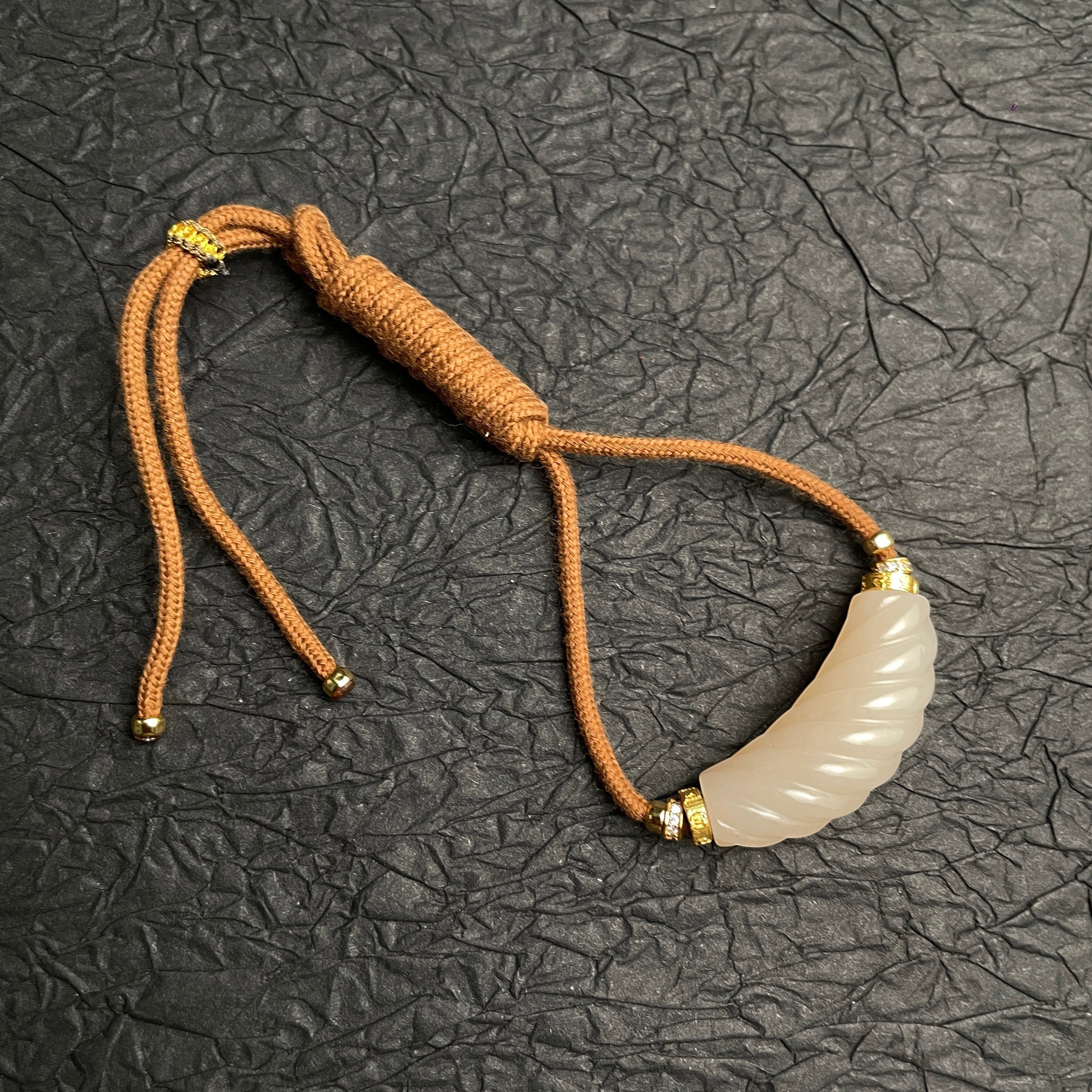 Sylvia Jewelry 粉色和田玉扭转吊坠,金色镀层点缀,搭配棕色绳链。