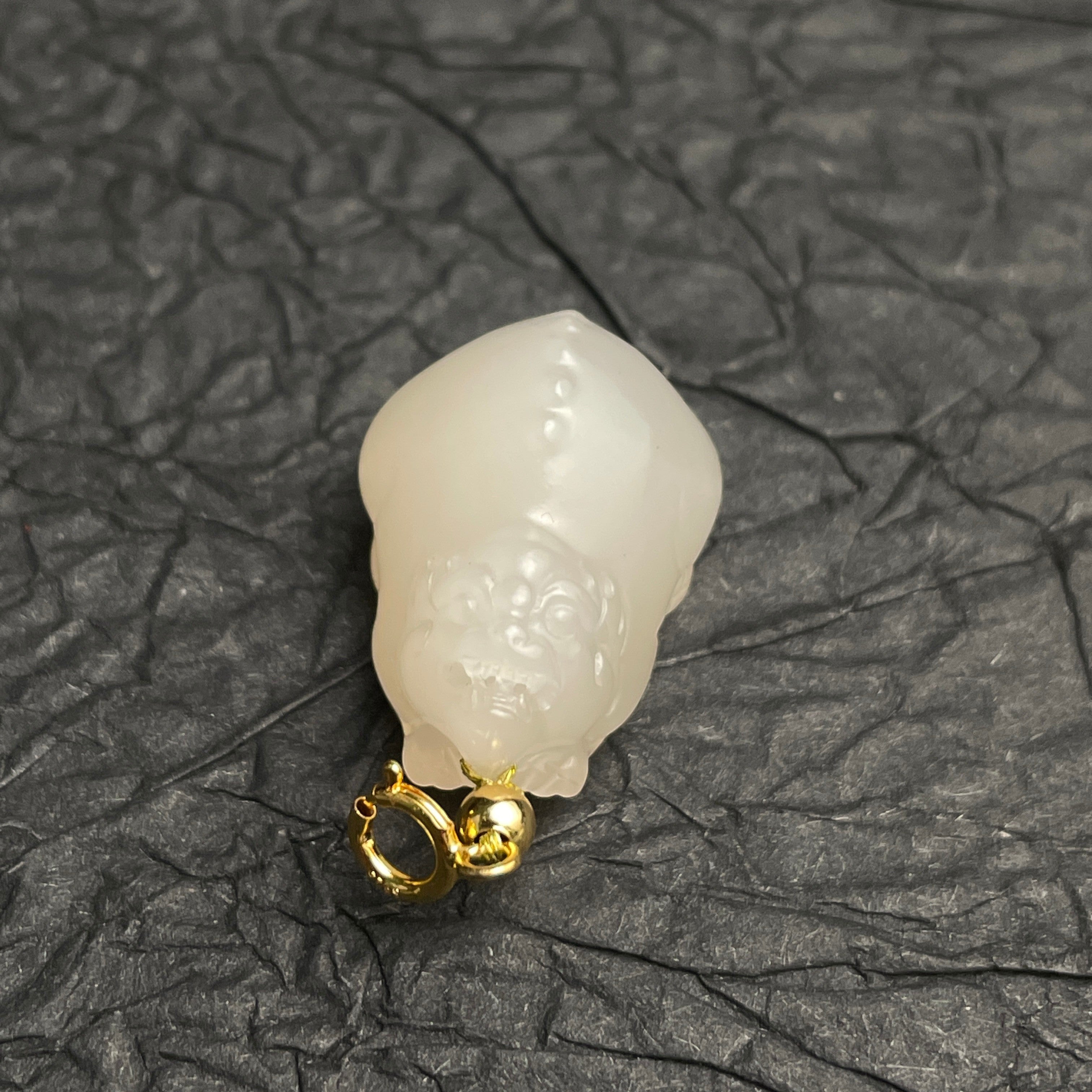 Sylvia Jewelry lotus-root pink Hetian nephrite jade PiXiu charm with a gold-plated spring clasp on a black textured base.
