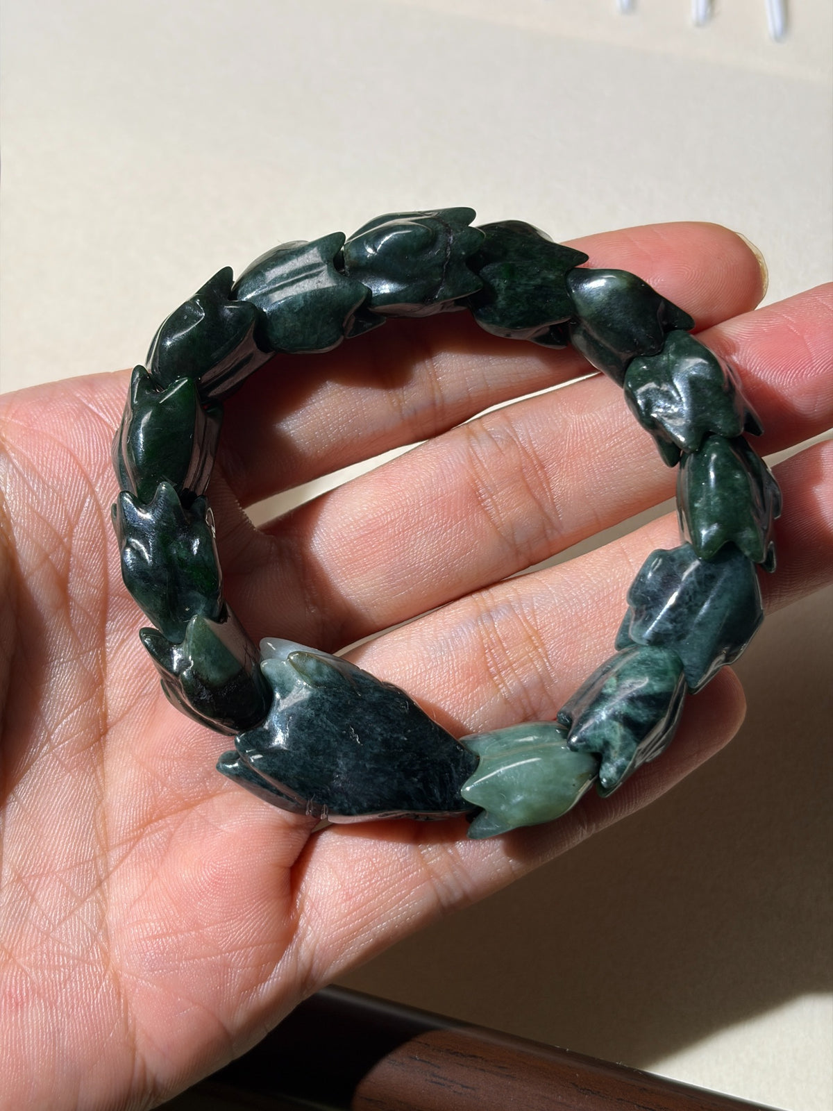 Close detail of dark and pale green carved jadeite beads on stretch bracelet
