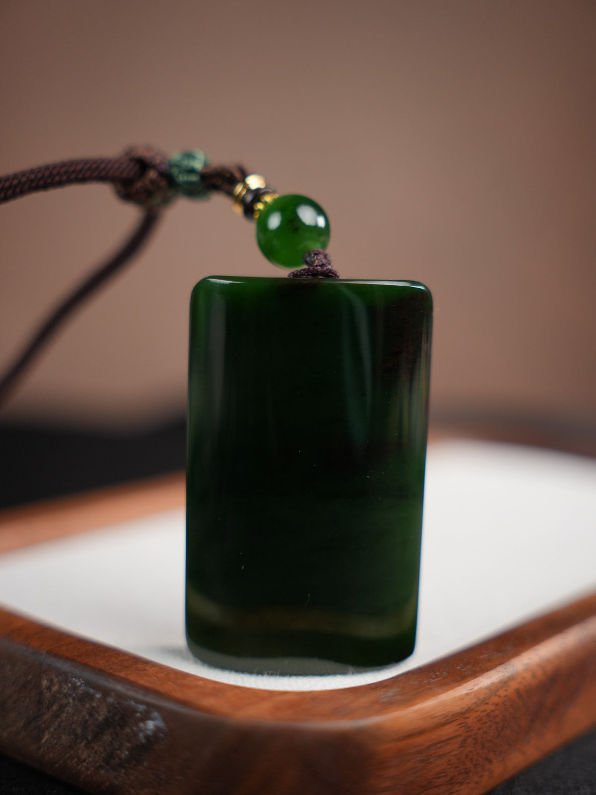 Deep green rectangular Hetian nephrite jade pendant with braided cord and green accent bead