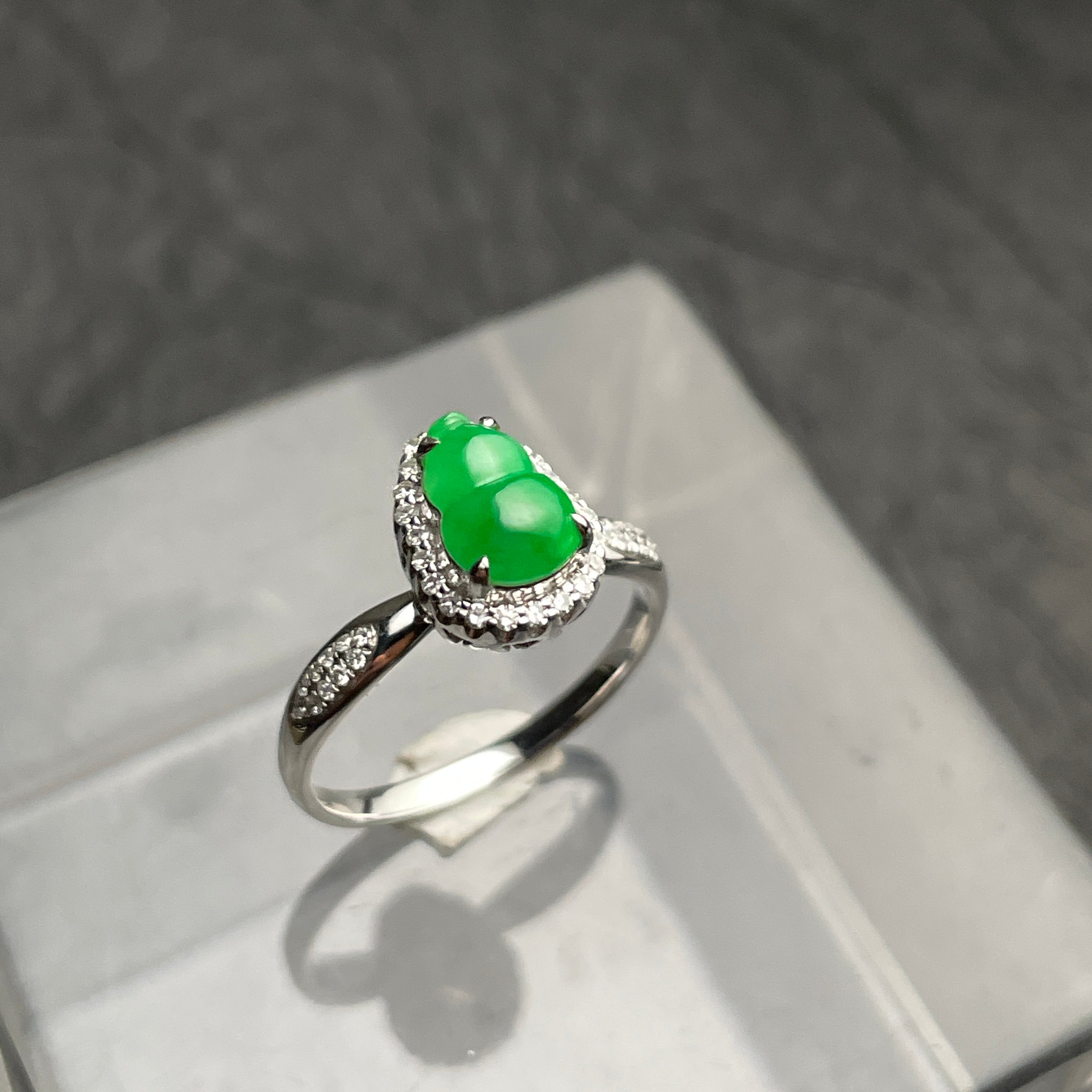 A green carved gourd ring with a clear halo and silver-tone band. Angled view.