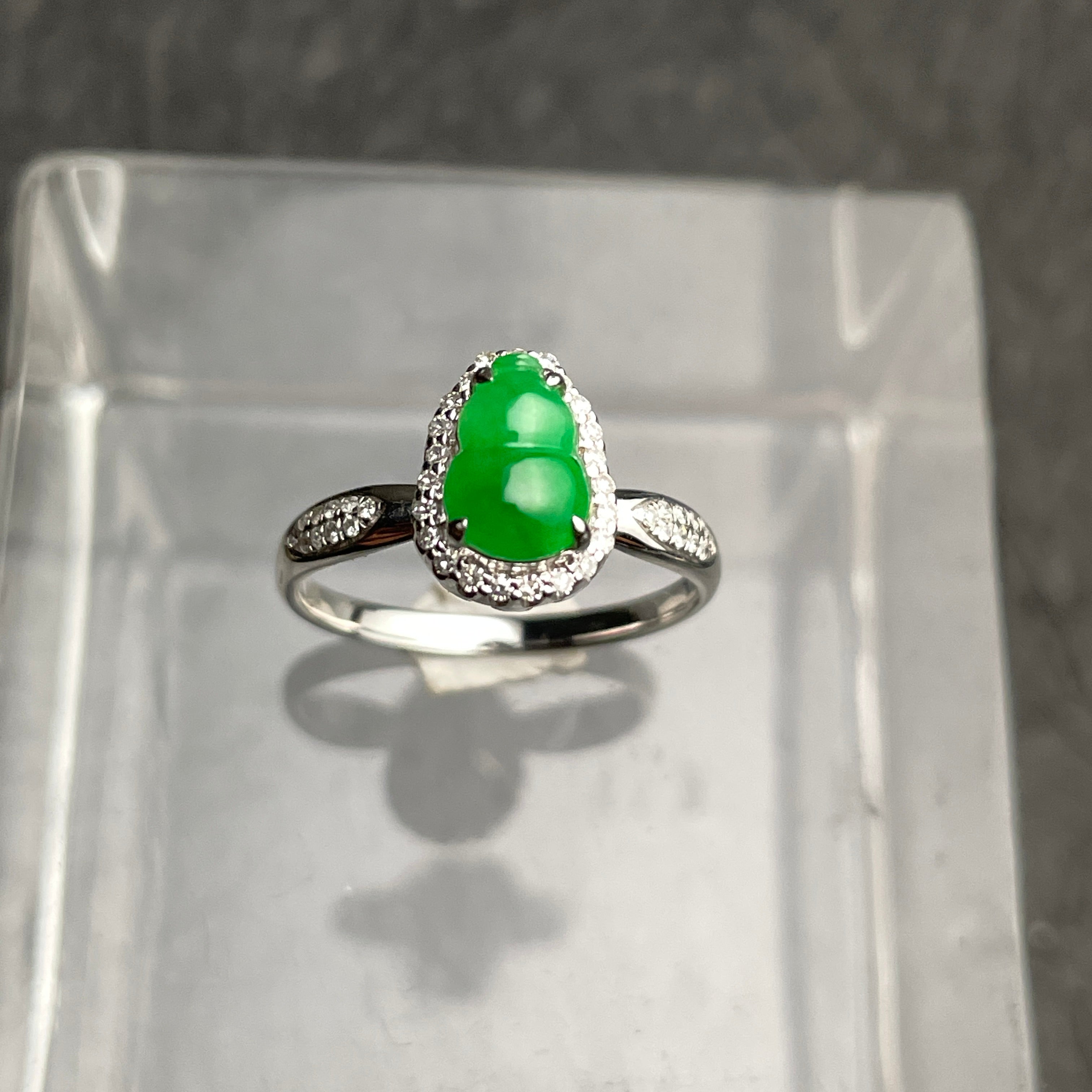 A green carved gourd ring with a clear halo and silver-tone band. Front view.