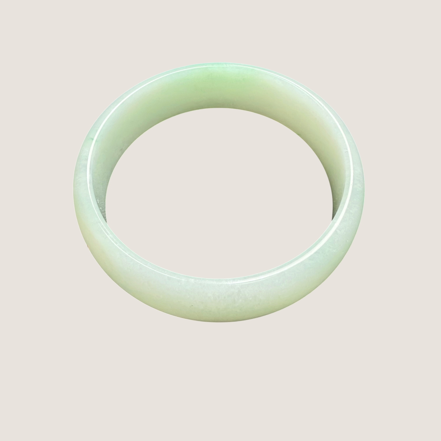 Green jade bracelet on a light beige background