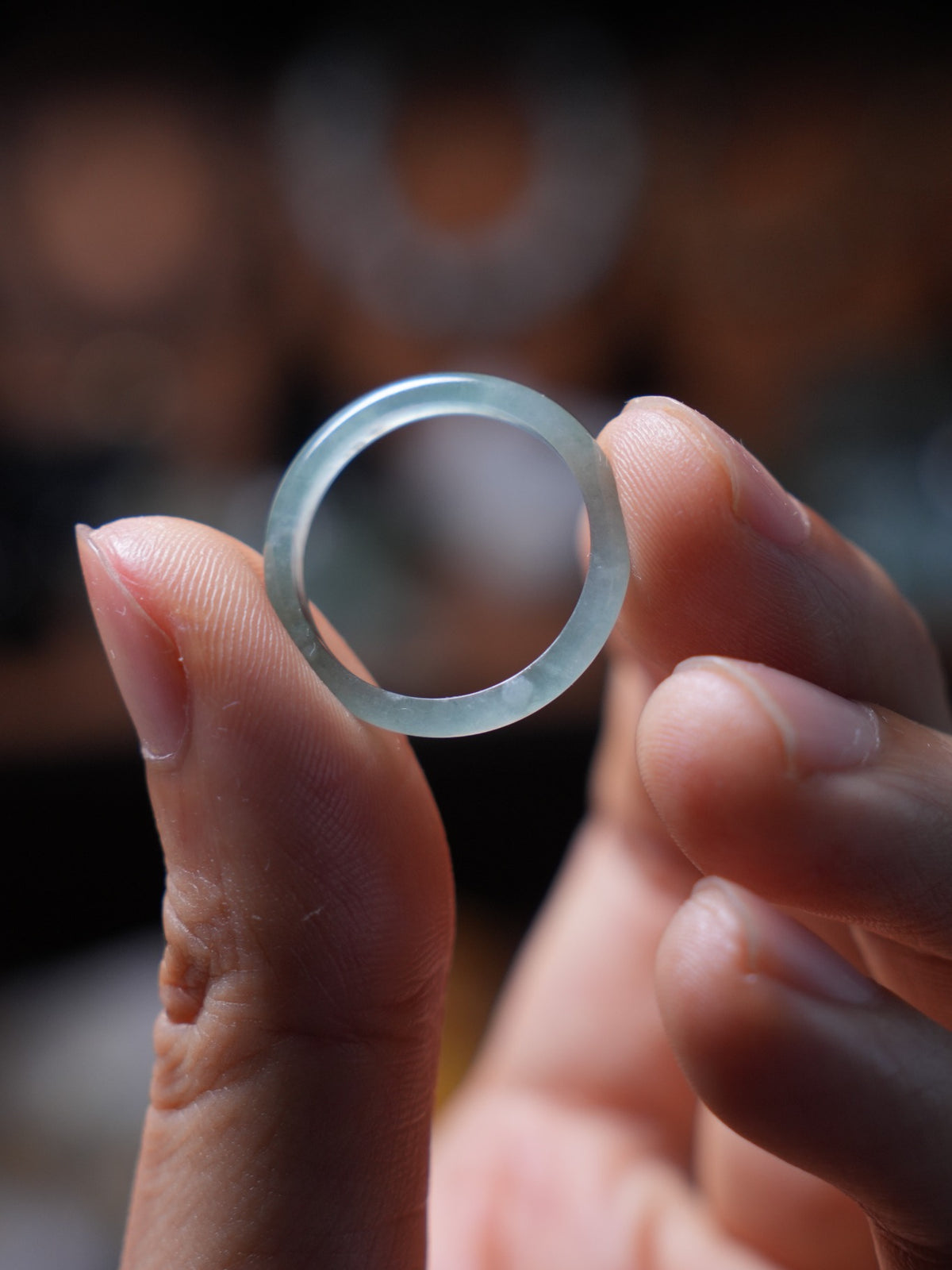 Green jadeite band ring held between fingers