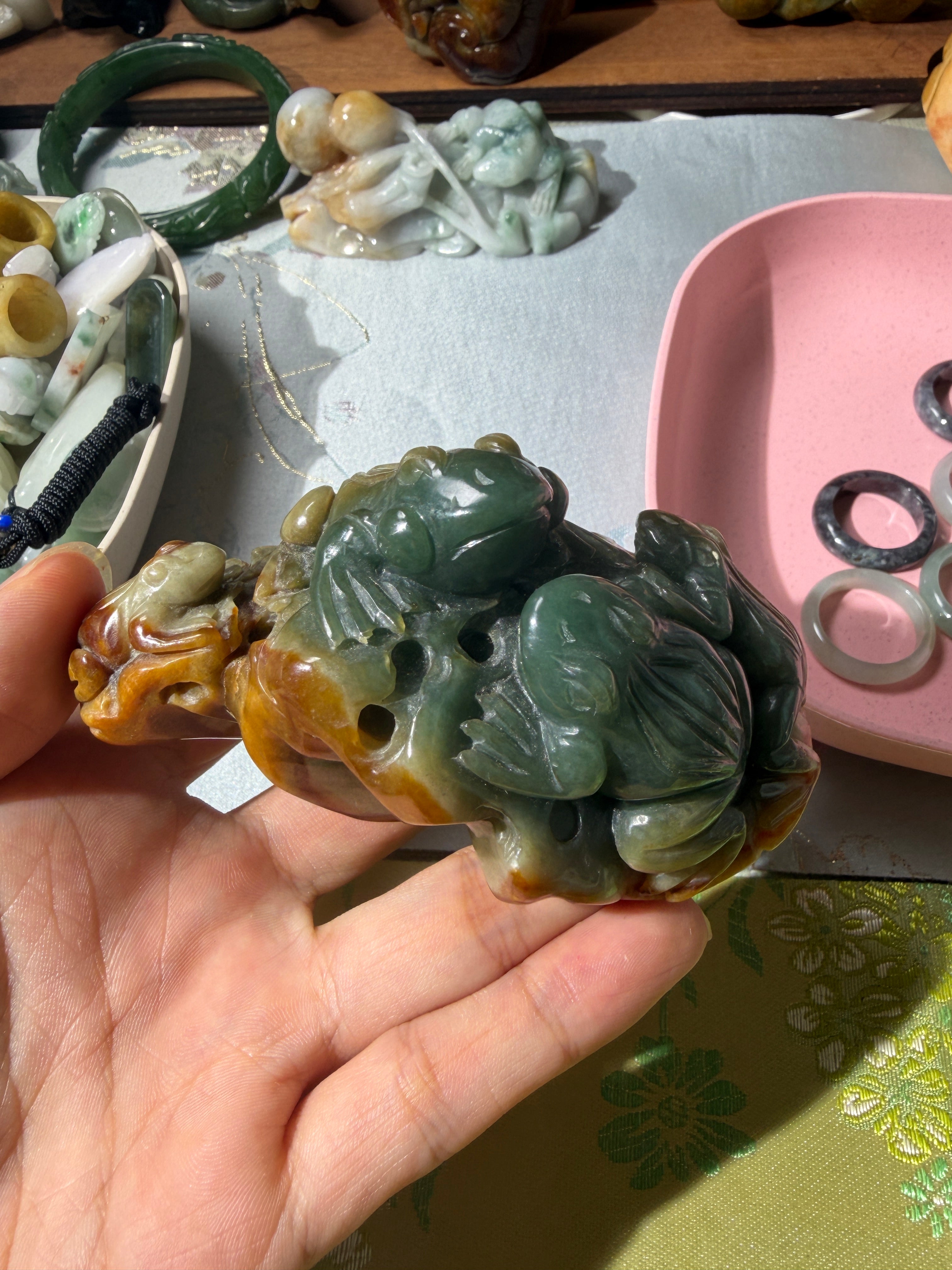 Carved jadeite frog display piece with natural green and russet tones