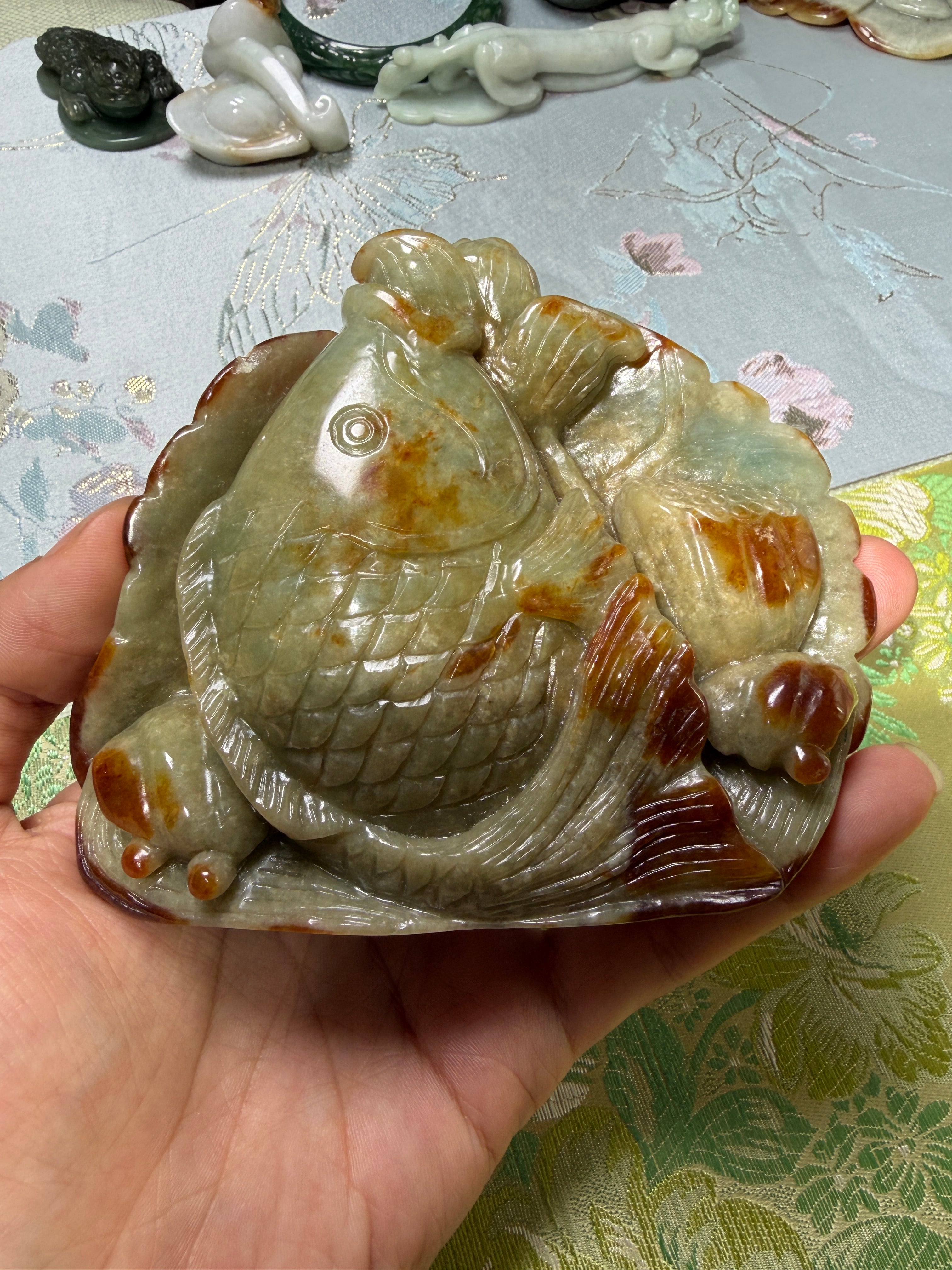 Carved jadeite koi fish display piece with natural green and russet tones
