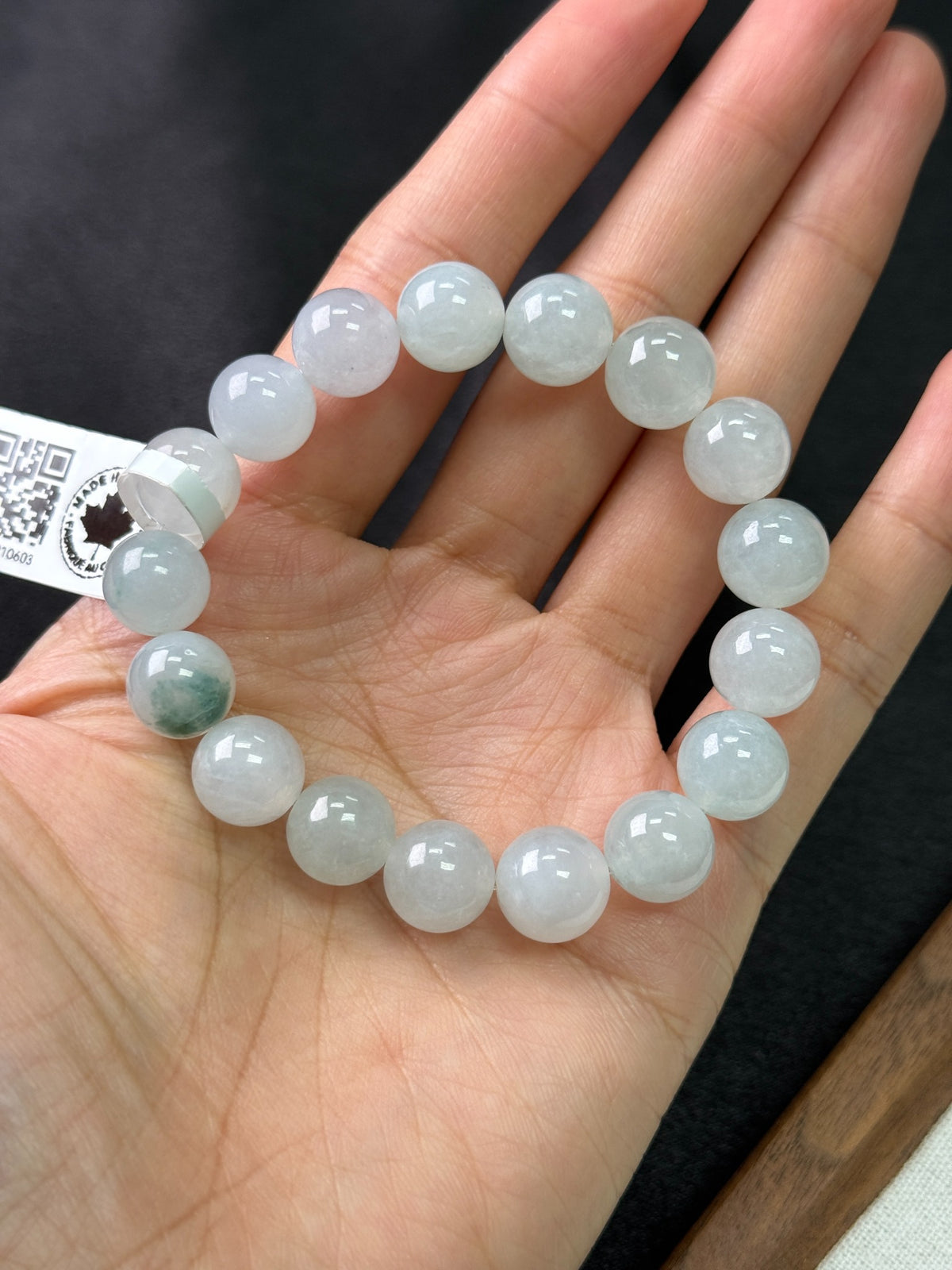 10.5 mm pale green jadeite bead bracelet shown on a hand, with one darker green bead