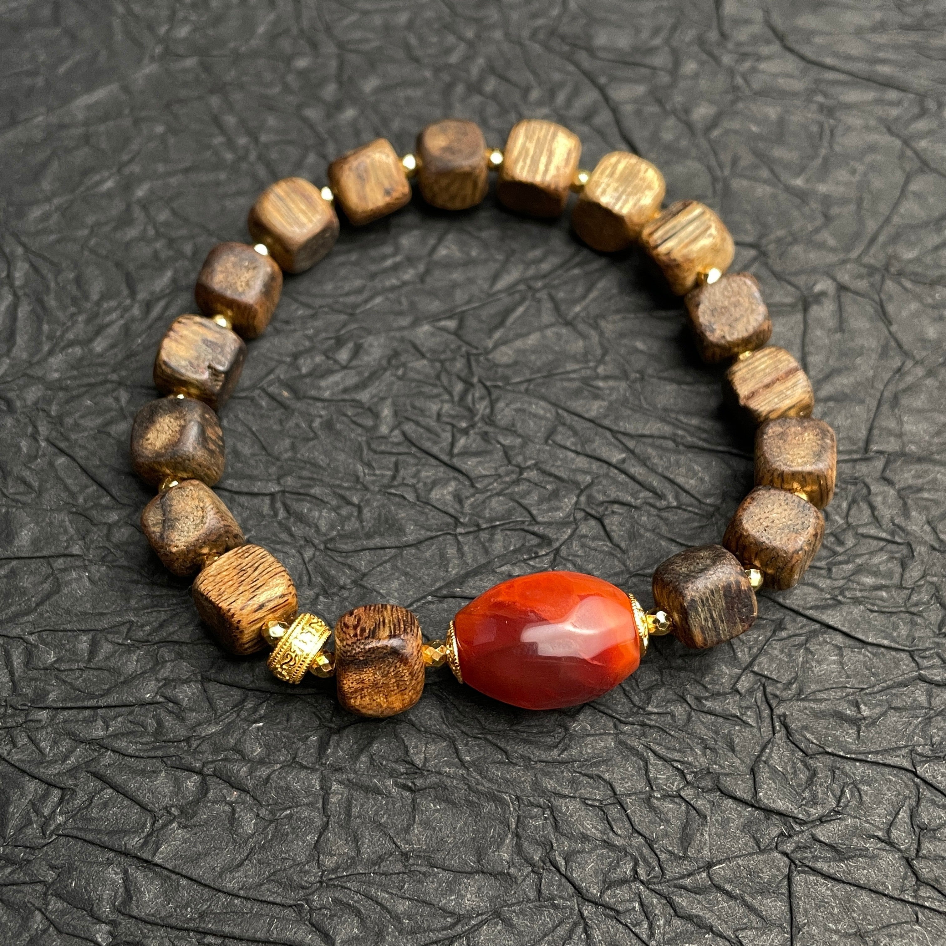 Sylvia Jewelry agarwood cubic block bracelet with a central red Nanhong agate barrel bead and gold-plated spacers.