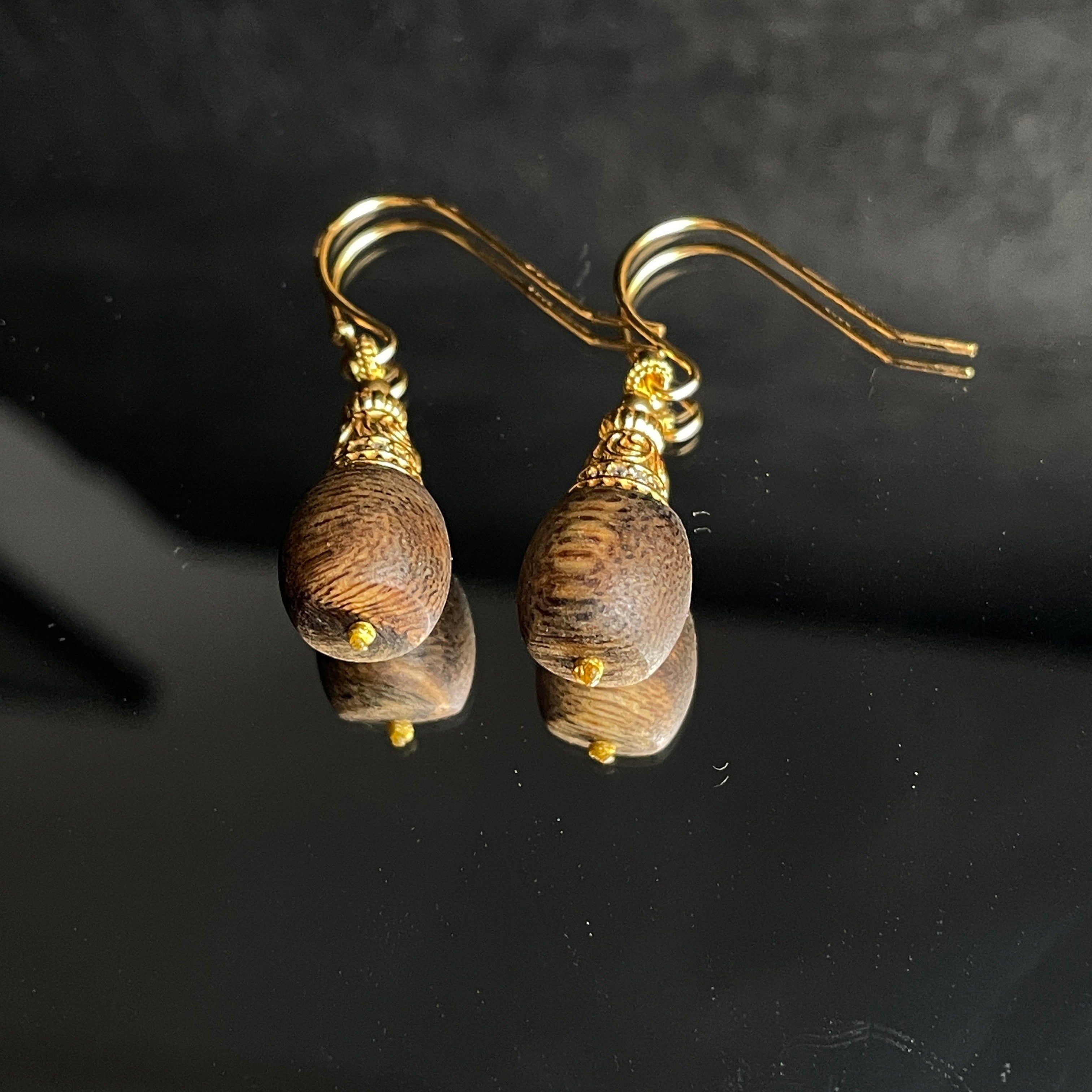 Sylvia Jewelry agarwood drop earrings featuring natural dark wood, crystal-paved gold filigree caps, and gold wire hooks.