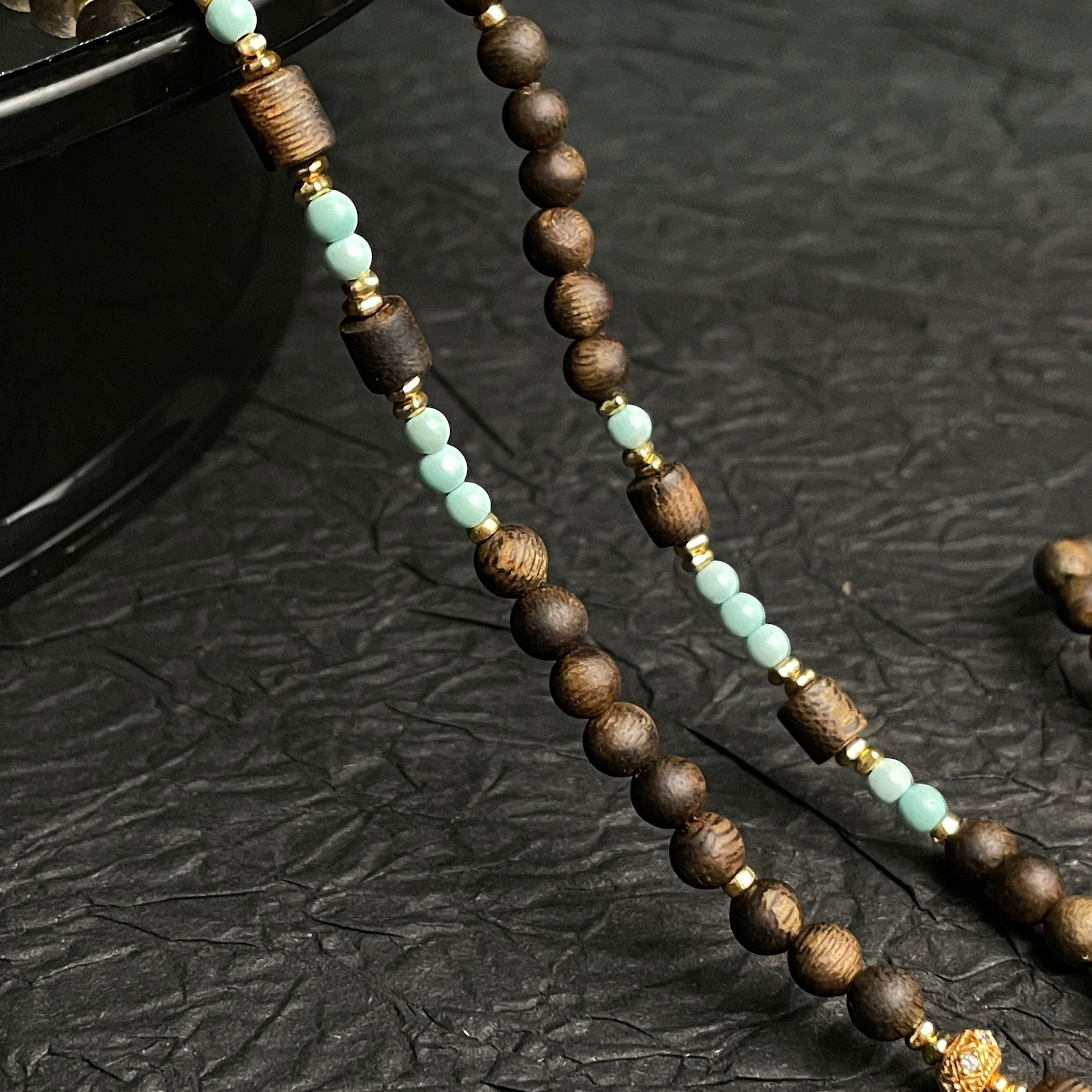 Sylvia Jewelry long necklace featuring natural agarwood beads, mint-green high-porcelain turquoise, and gold accents.