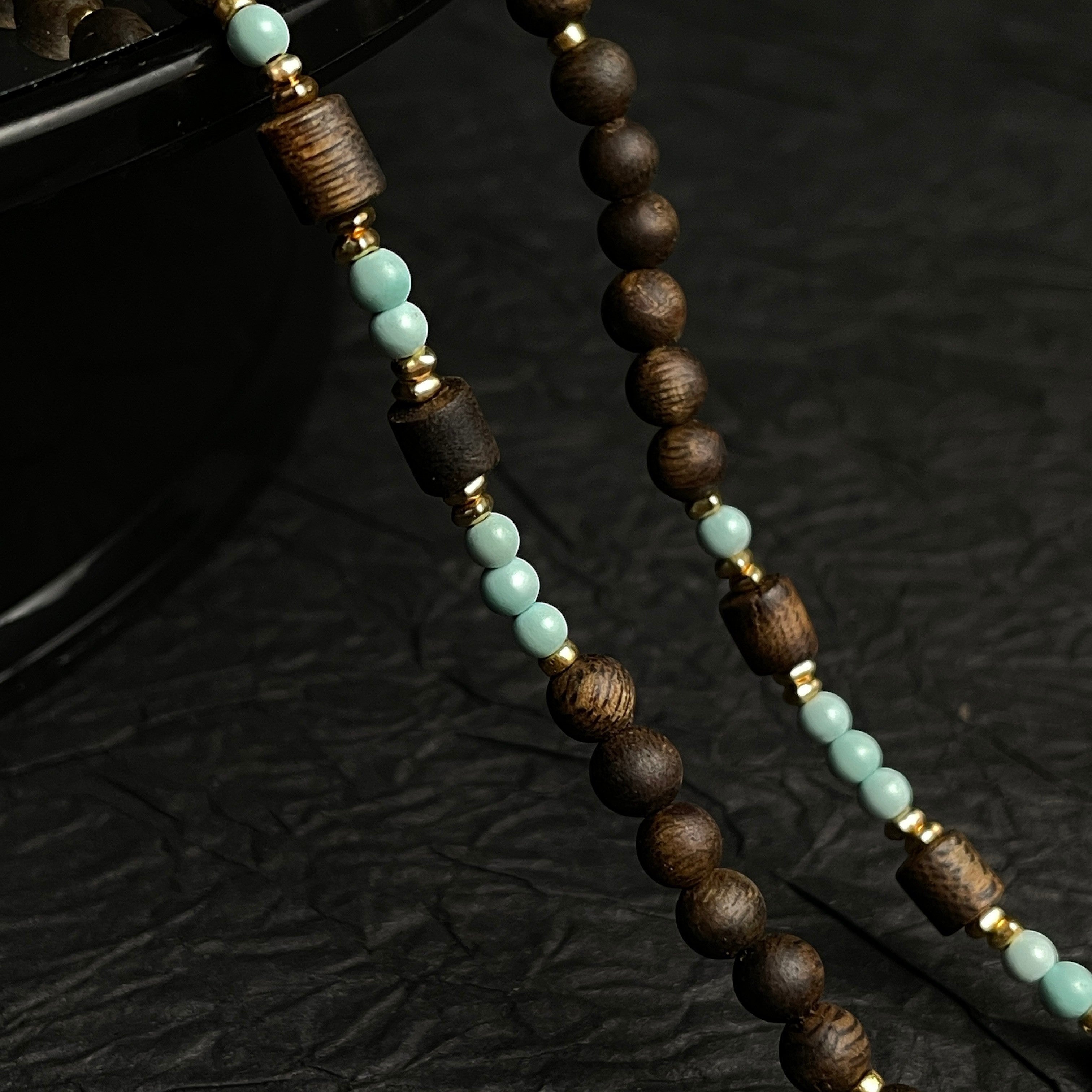 Sylvia Jewelry long necklace featuring natural agarwood beads, mint-green high-porcelain turquoise, and gold accents.