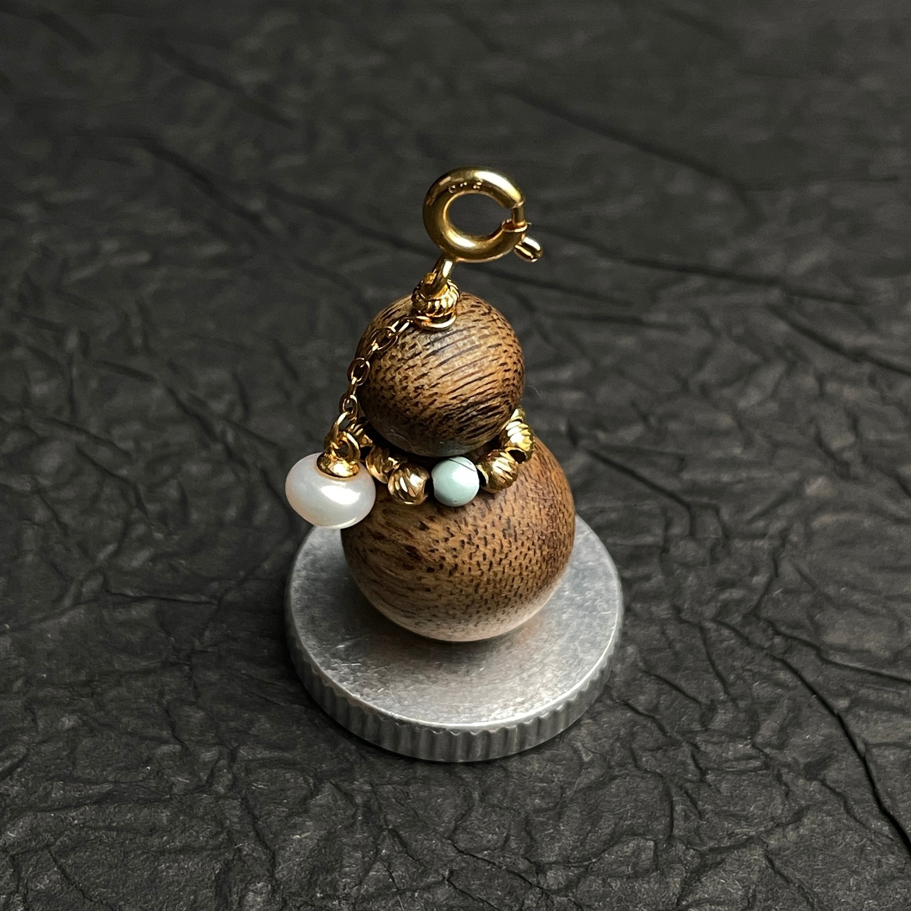Sylvia Jewelry aromatic agarwood Wu Lou charm with turquoise, freshwater pearl, and gold hardware on a silver base.