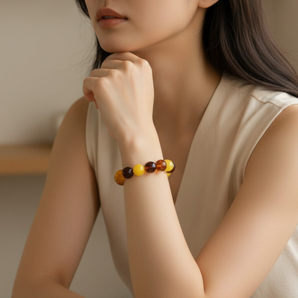 Sylvia Jewelry multi-variety Baltic amber and beeswax stretch bracelet worn by a woman in a beige top.