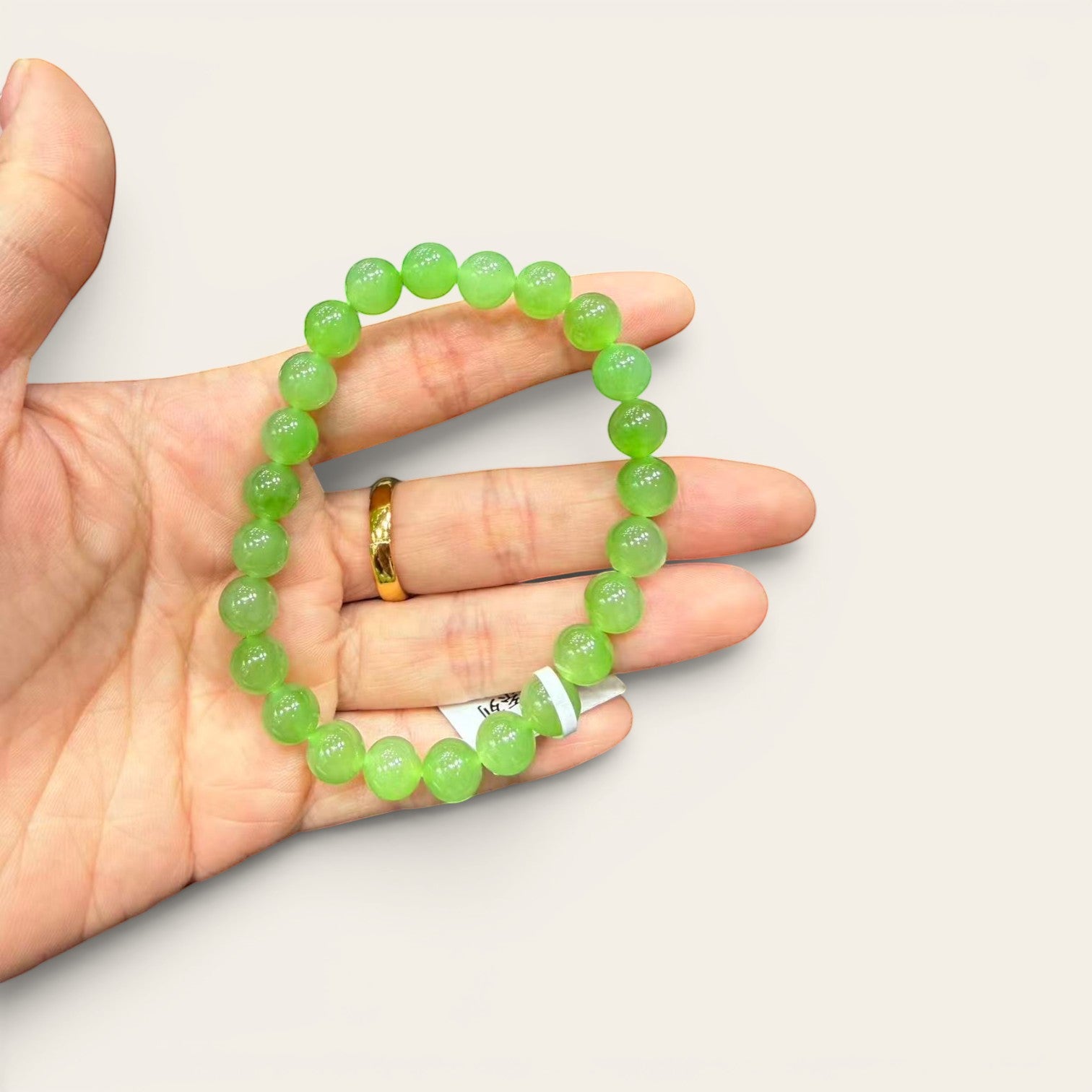 Sylvia Jewelry apple green Ulan-Ude nephrite jade bead bracelet held in a hand, showing vibrant translucent green stones.
