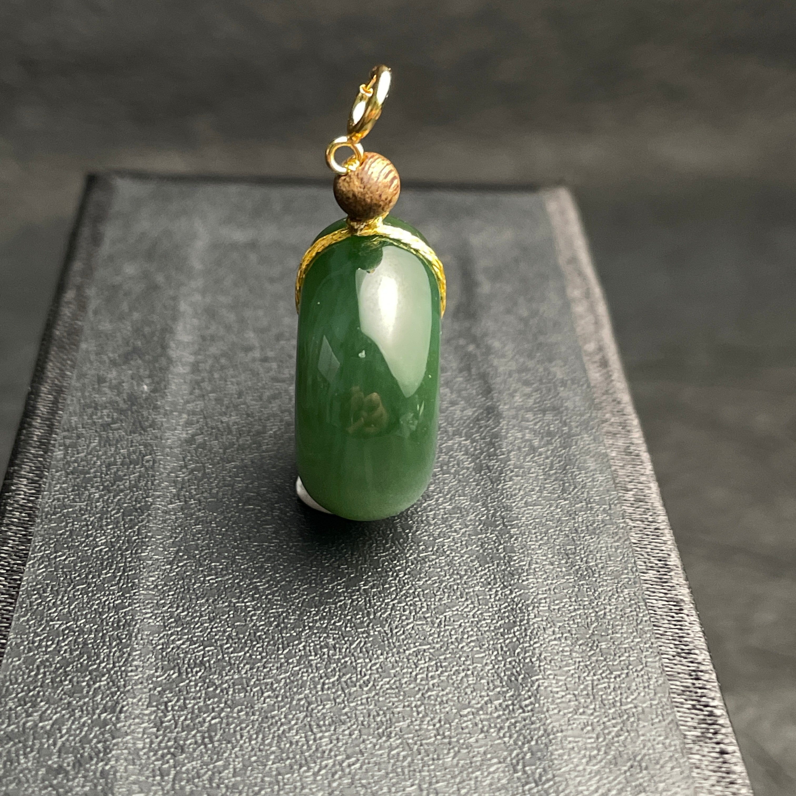 Sylvia Jewelry dark green jade donut pendant with gold wire wrapping and a small wooden bead on a black display box