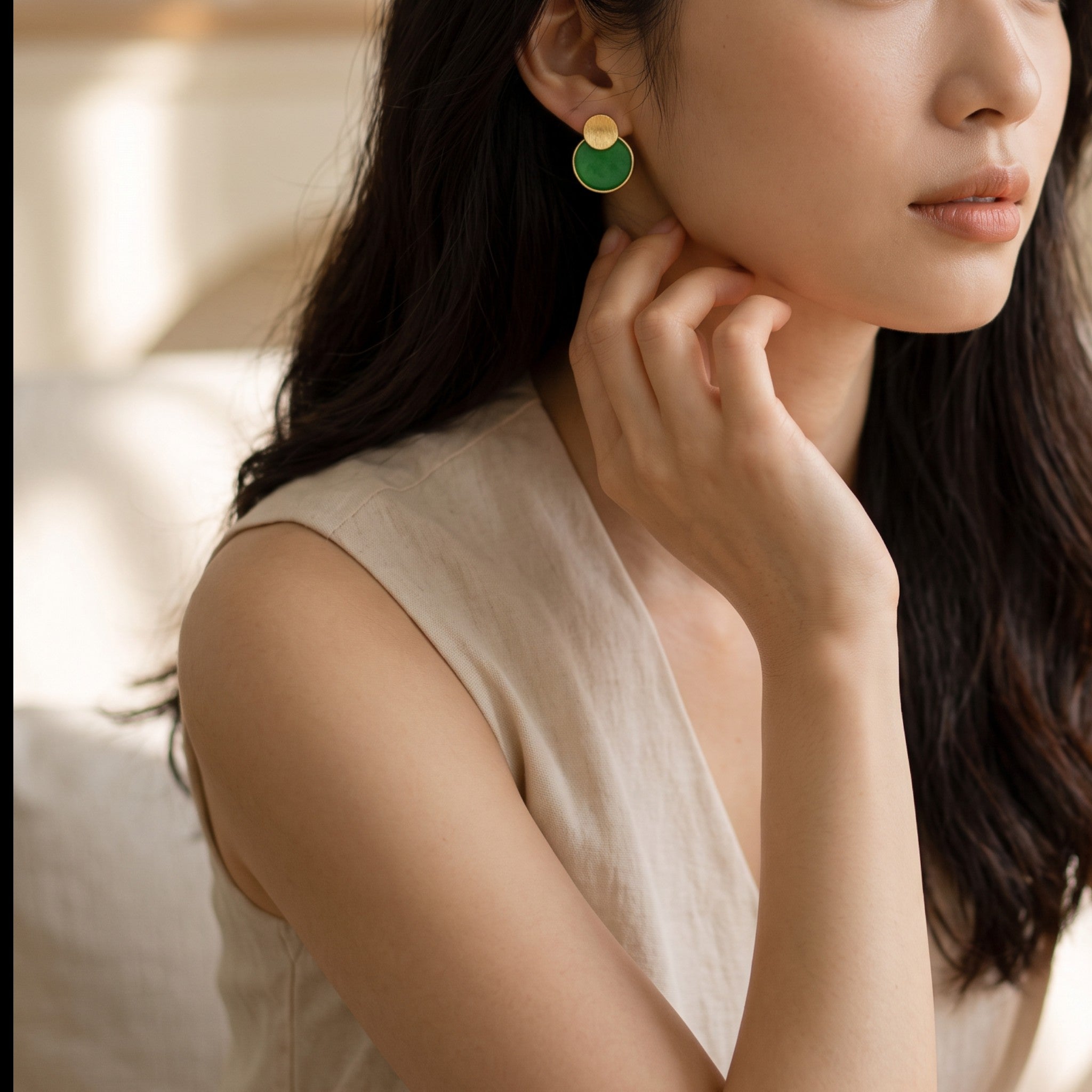 Sylvia Jewelry 18K gold and green jadeite disc drop earrings worn by a woman in a neutral top