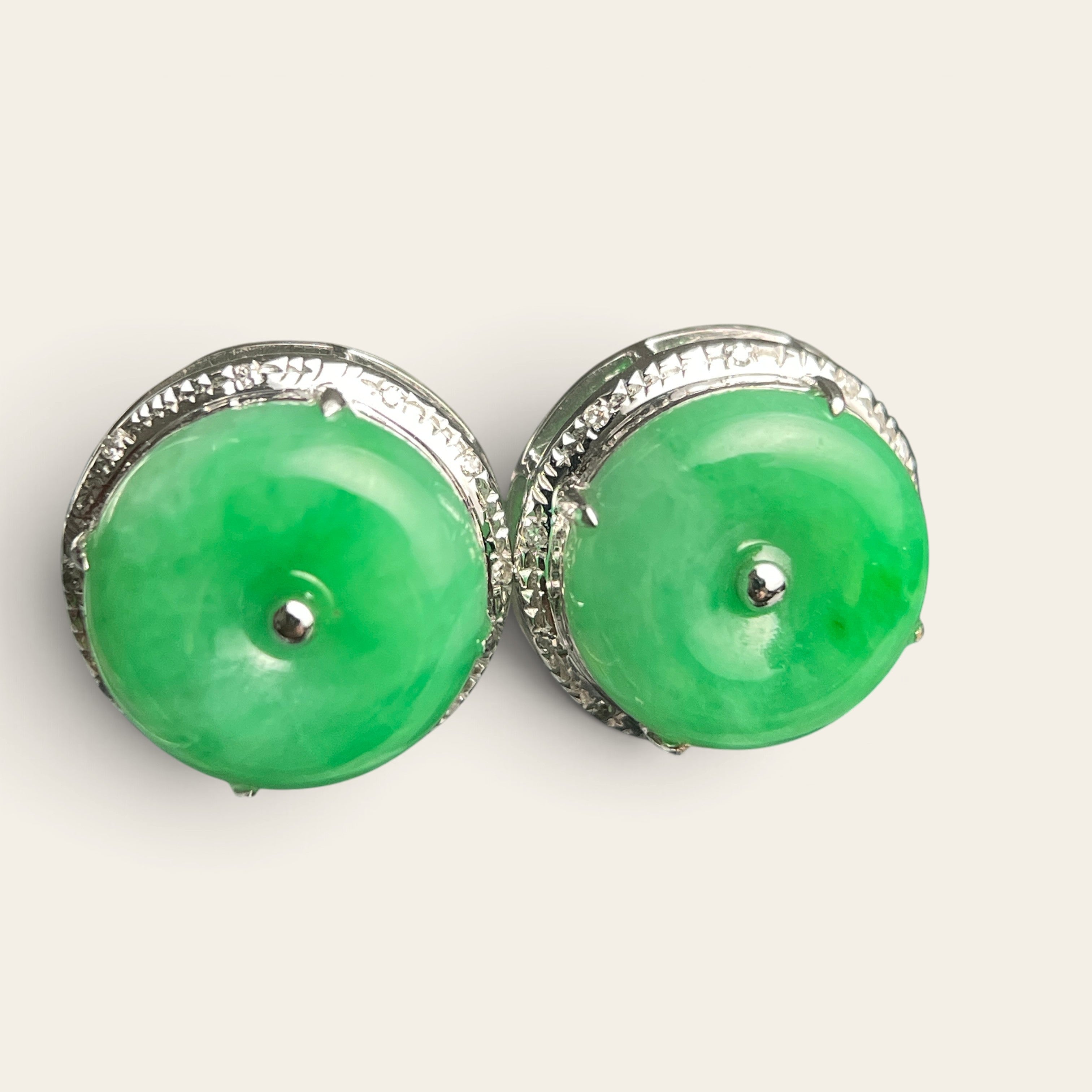 Sylvia Jewelry green jadeite disc stud earrings with silver-tone textured metal frames on a reflective surface.