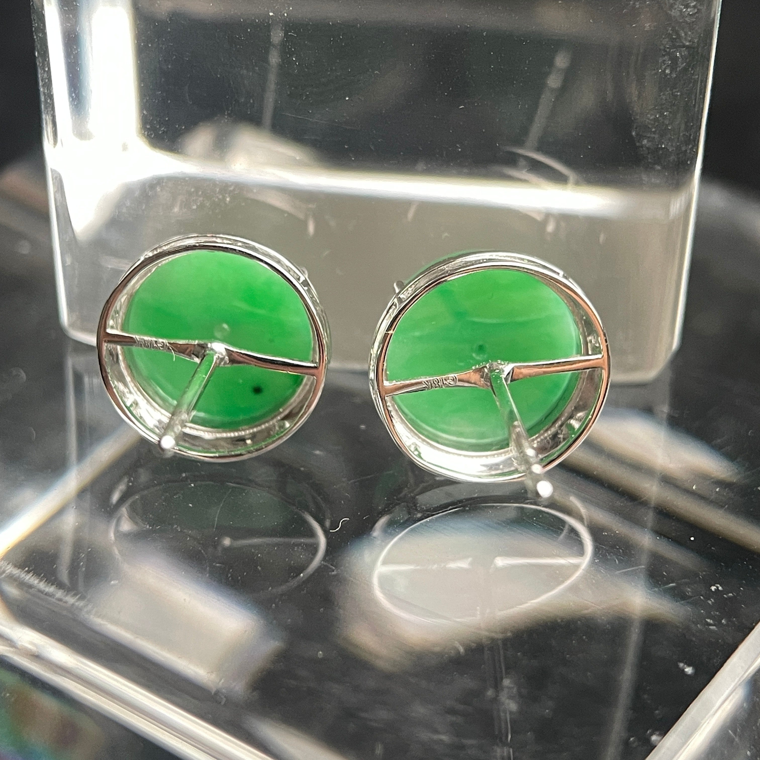 Sylvia Jewelry green jadeite disc stud earrings with silver-tone textured metal frames on a clear display stand.