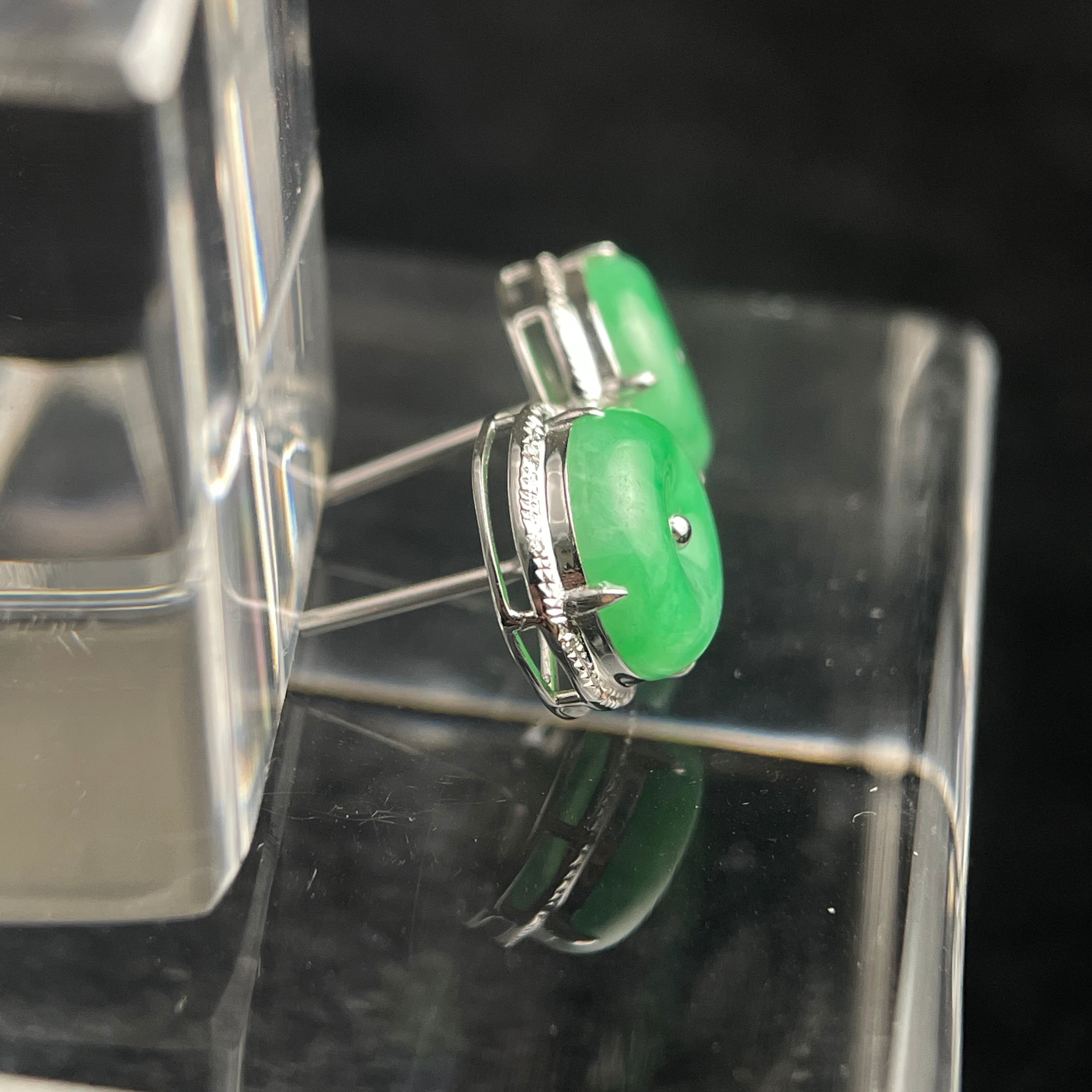 Sylvia Jewelry green jadeite disc stud earrings with silver-tone textured metal settings on a clear display stand.