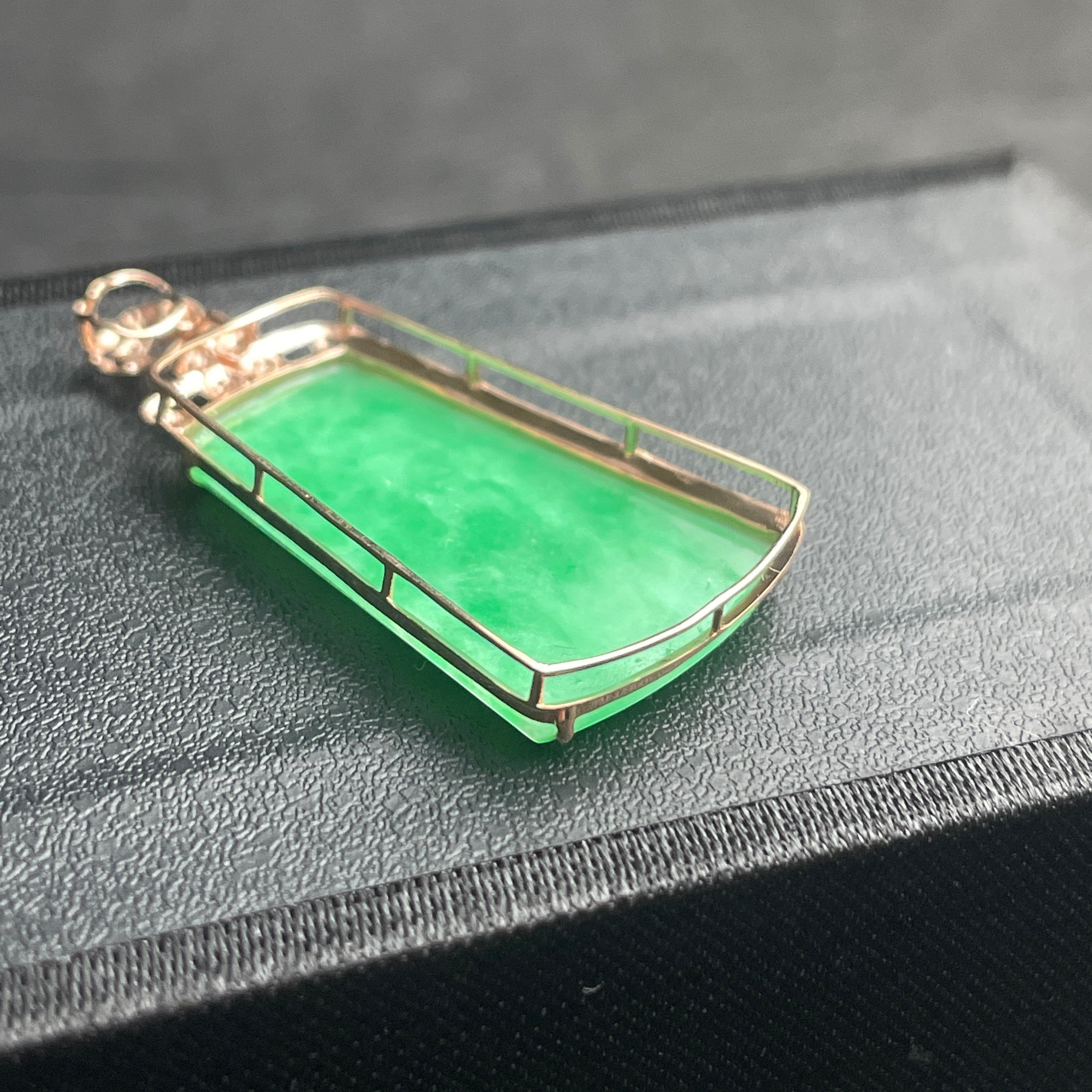 Sylvia Jewelry apple green jadeite trapezoid pendant in 18k gold setting on a black display box.
