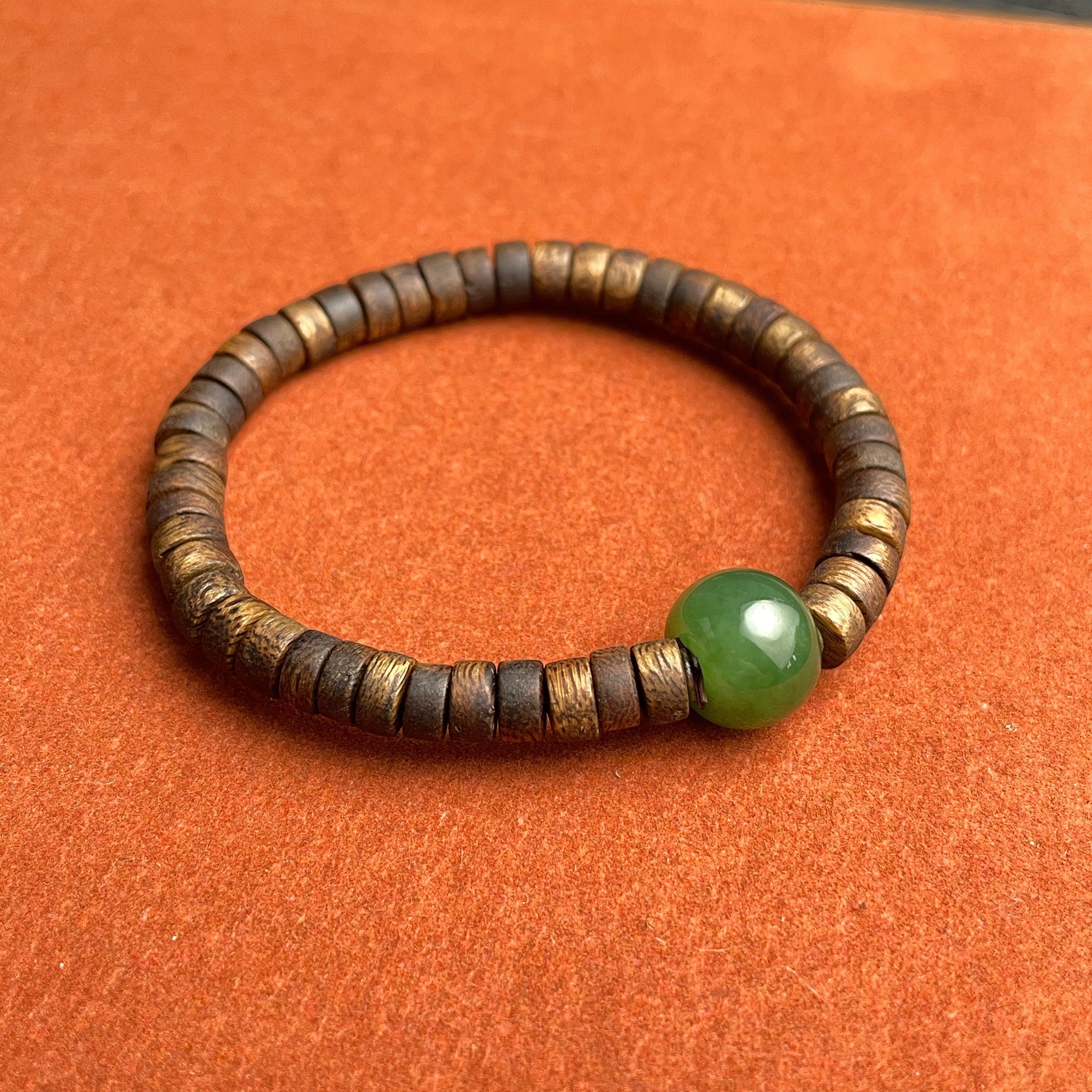 Sylvia Jewelry bracelet featuring a spinach green Hetian nephrite jade bead and natural agarwood abacus spacer beads.