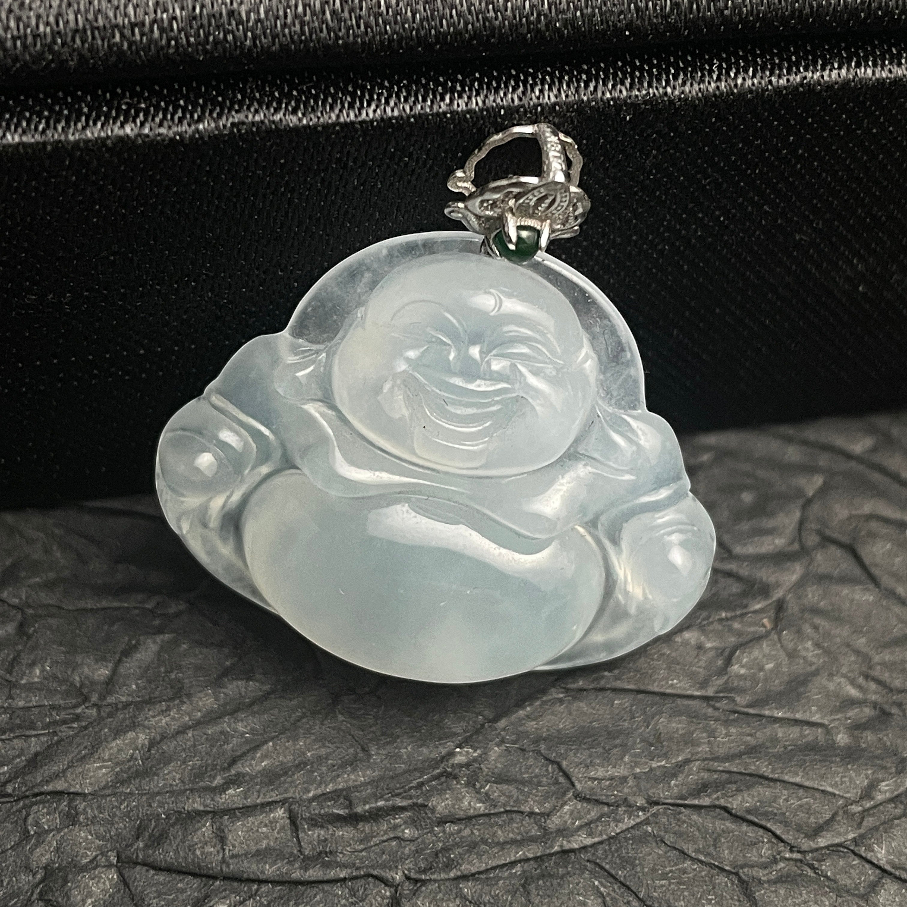 Sylvia Jewelry translucent icy jadeite laughing Buddha pendant with a delicate silver bail on a black textured base.