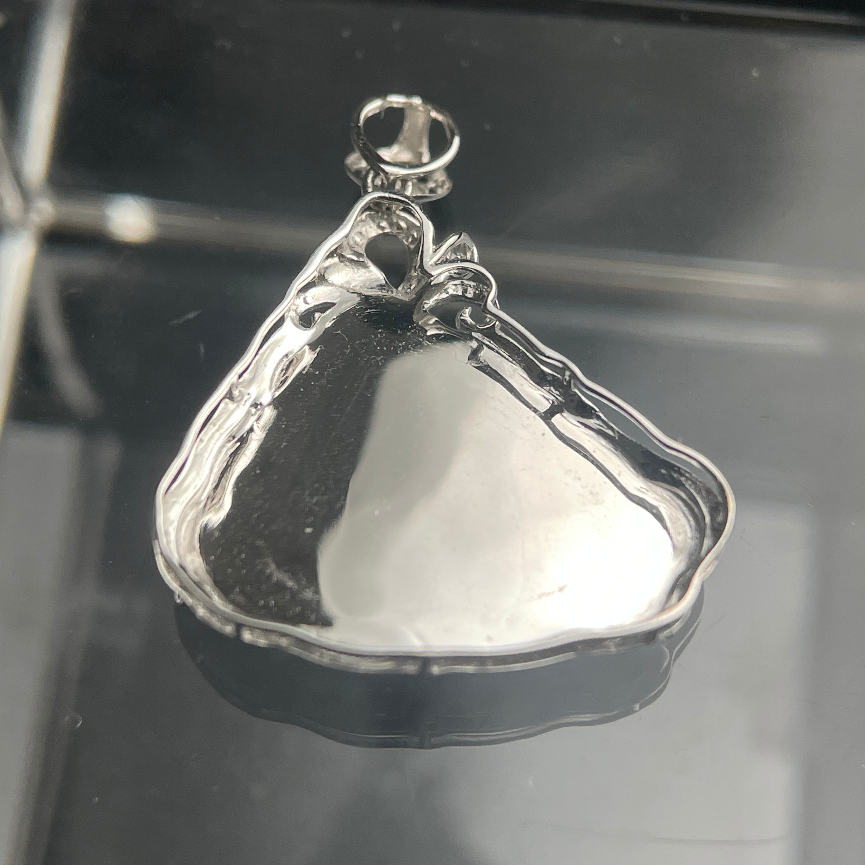 Sylvia Jewelry lotus pendant back view featuring polished 18K gold setting on a reflective black surface.