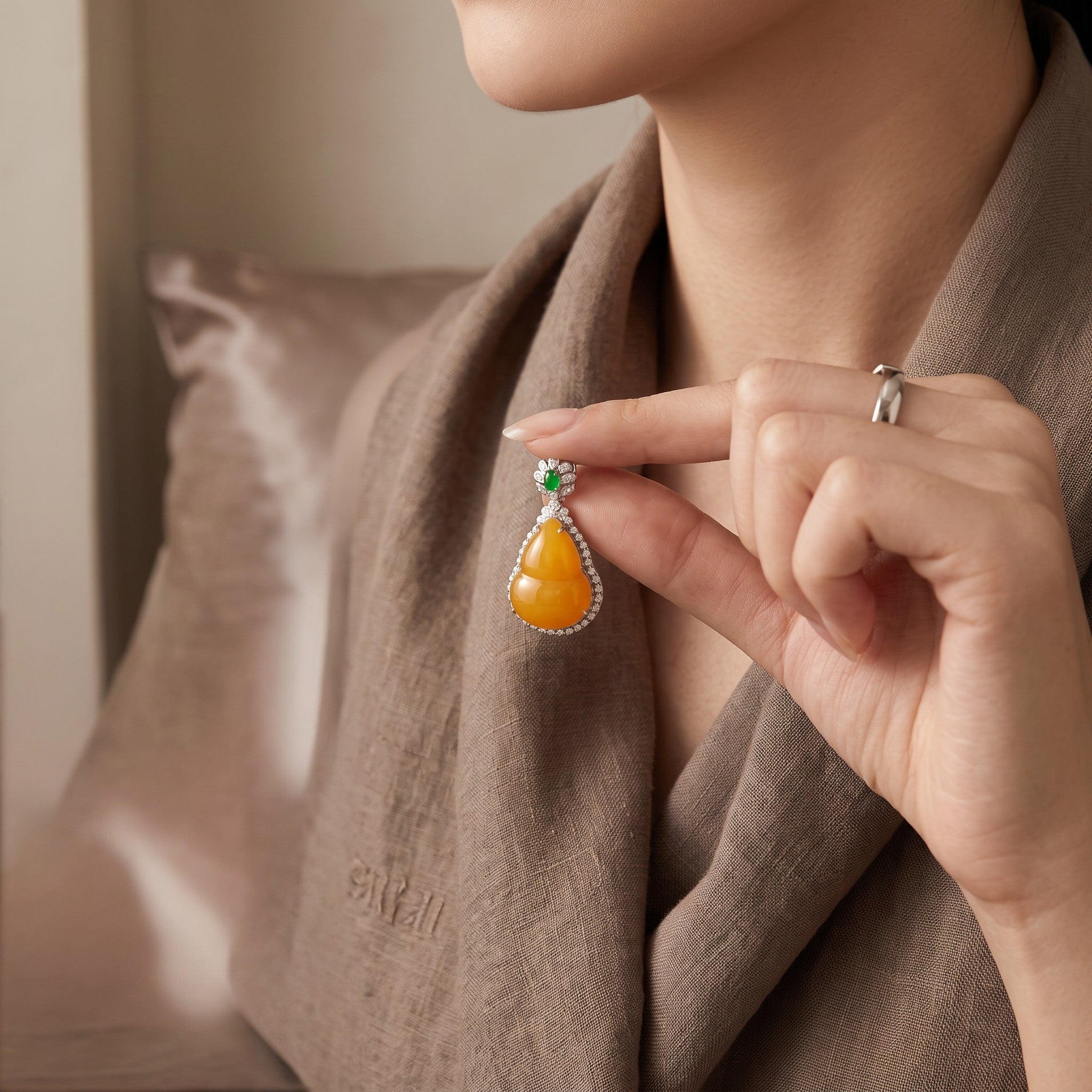 Sylvia Jewelry orange jadeite jade pendant with green jade accent and 18K gold setting worn by a woman.