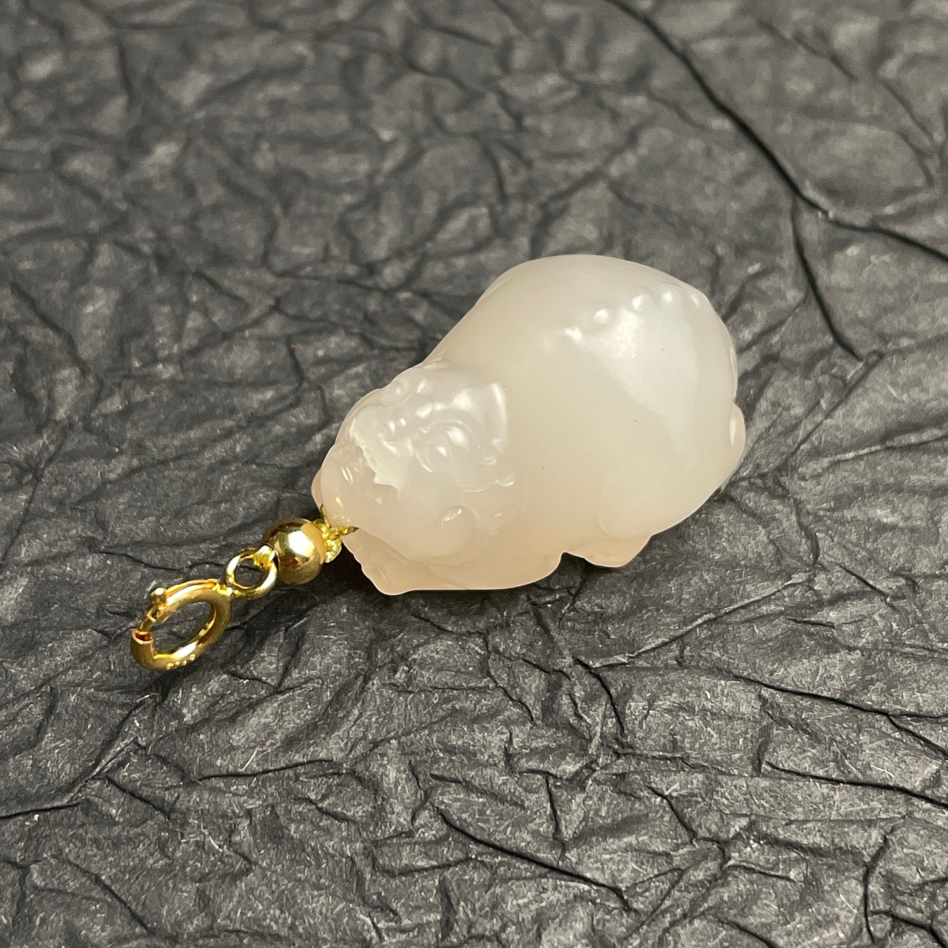 Sylvia Jewelry lotus-root pink Hetian nephrite jade PiXiu charm with gold clasp on a textured black background