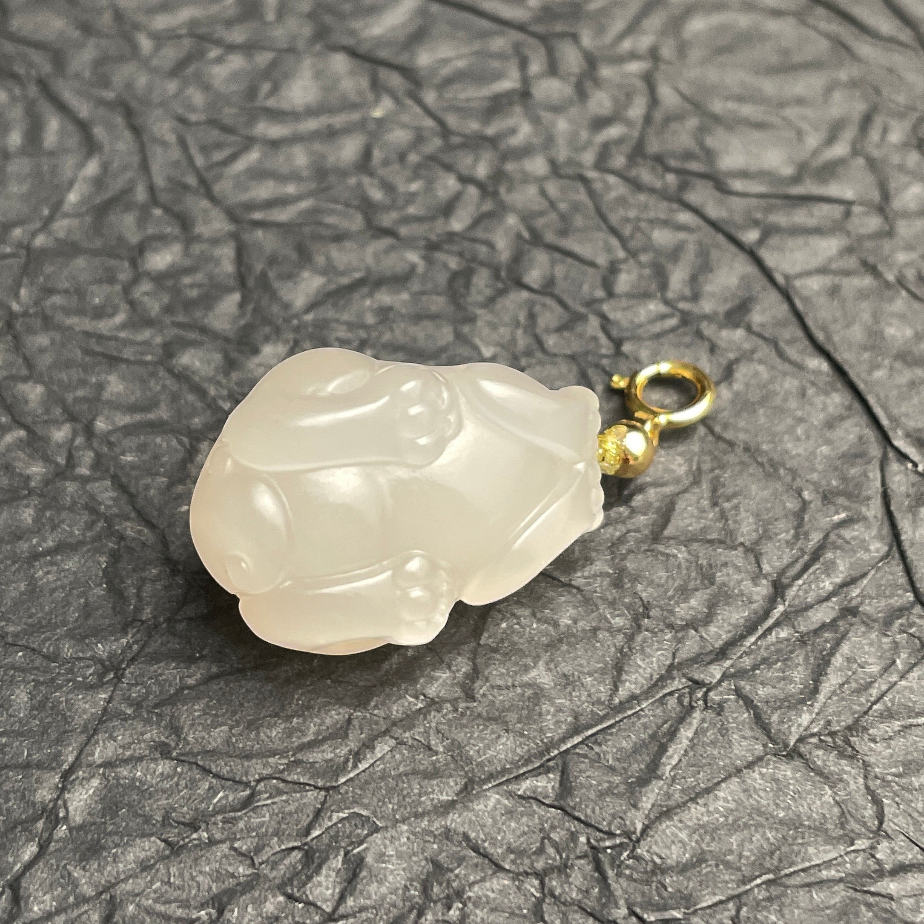 Sylvia Jewelry lotus-root pink Hetian nephrite jade PiXiu charm with a polished gold spring clasp on black paper.