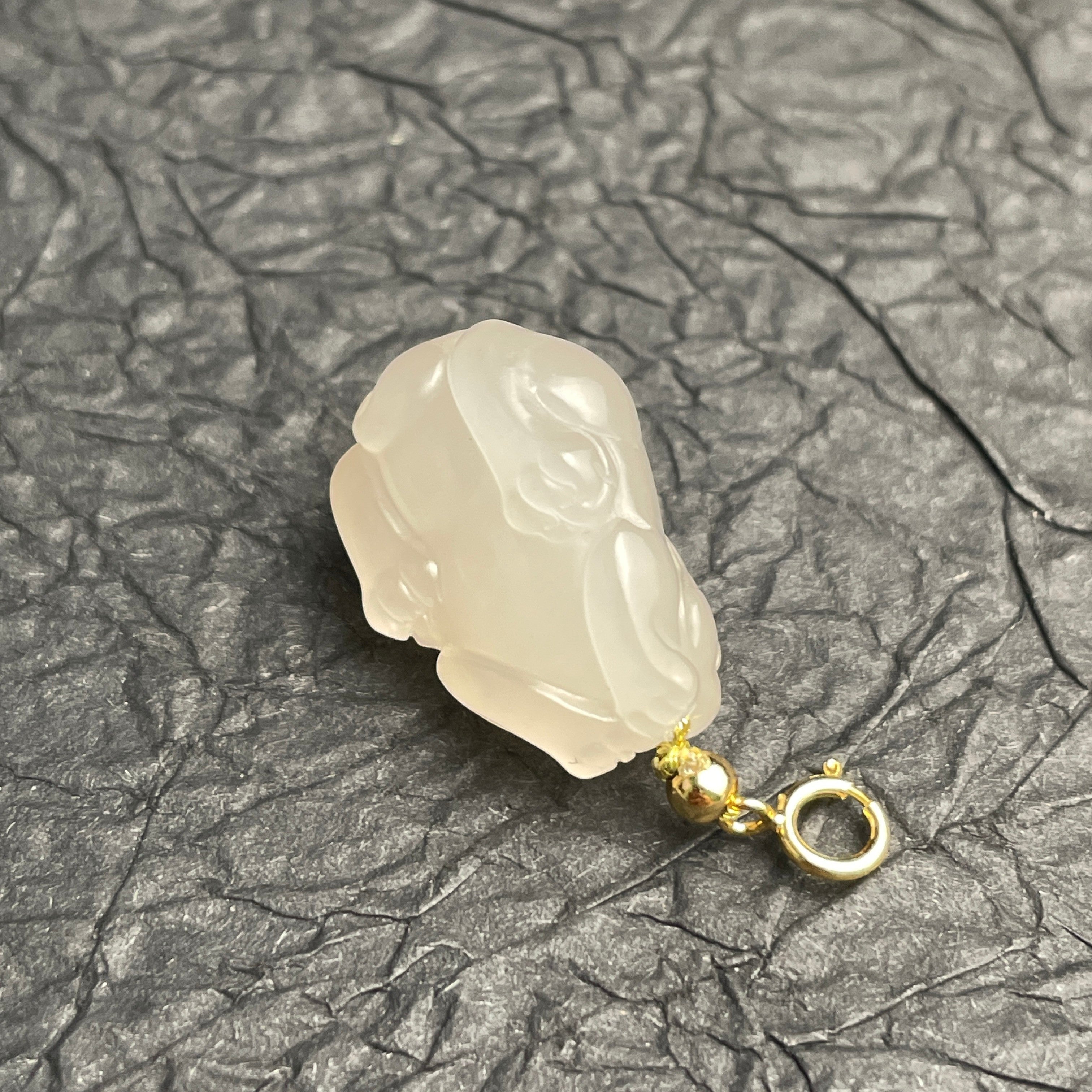 Sylvia Jewelry lotus-root pink Hetian nephrite jade PiXiu charm with a gold-plated spring clasp on a dark texture.