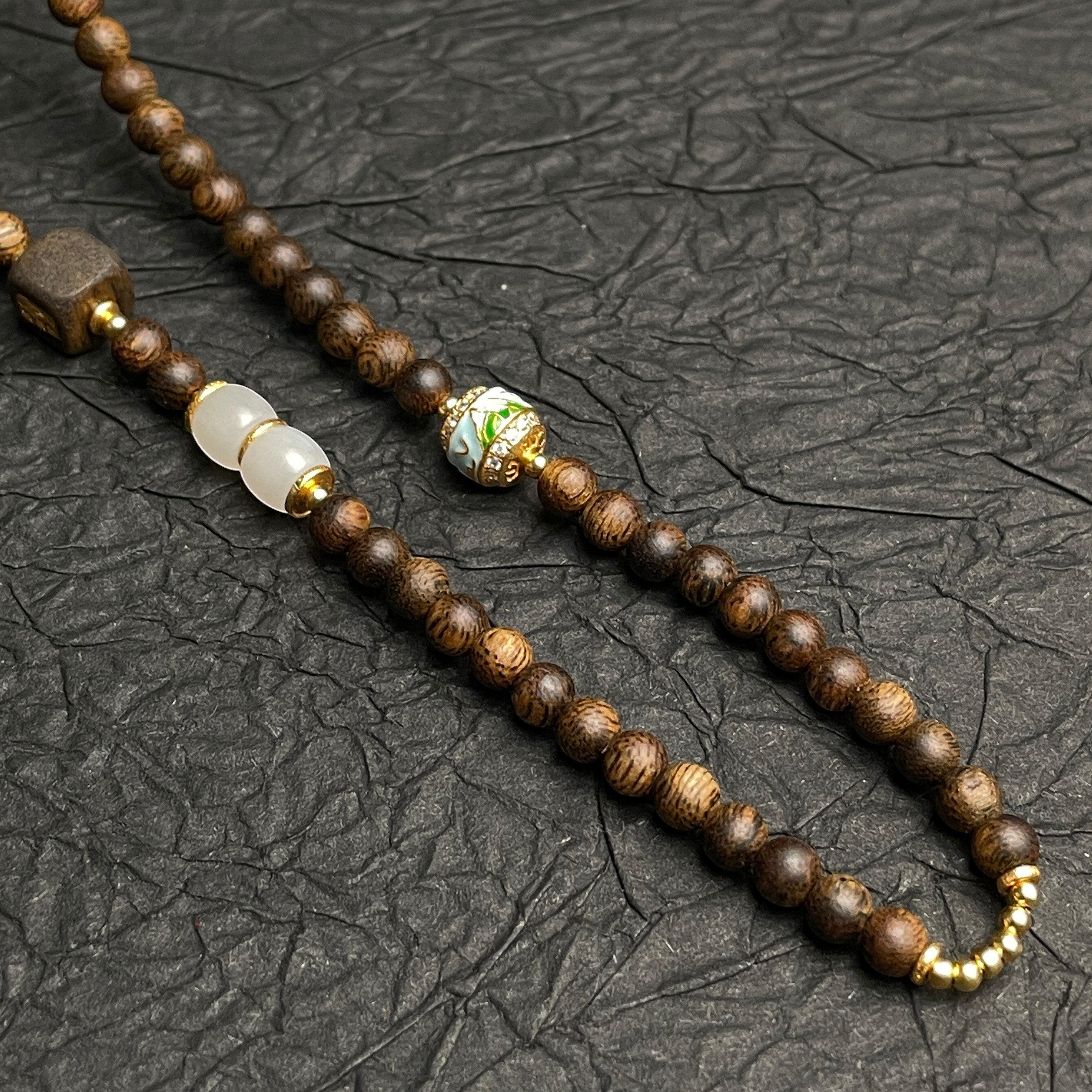 Sylvia Jewelry beaded necklace featuring dark wood beads, white jade, and a gold-accented floral cloisonne bead.