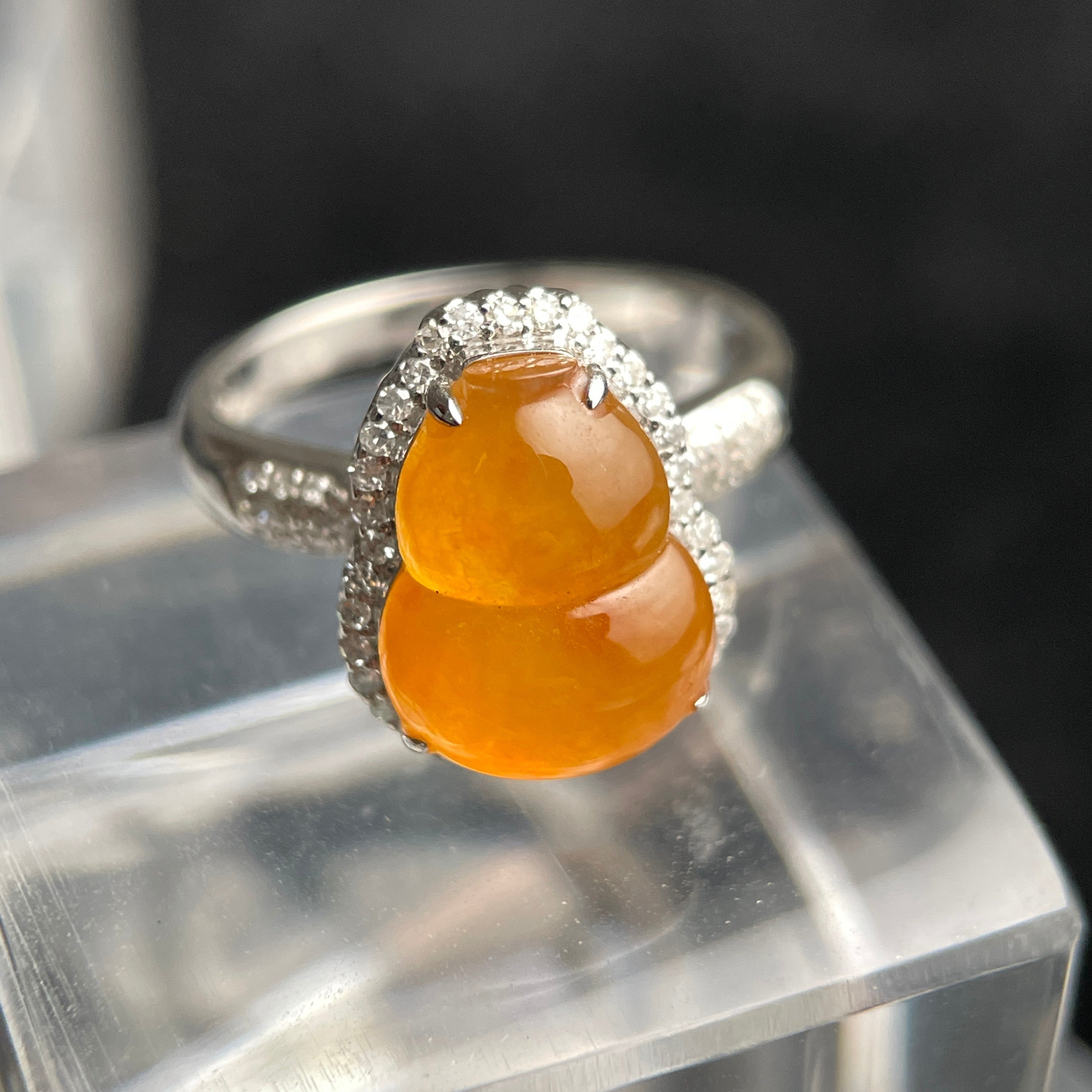 Sylvia Jewelry yellow jadeite gourd ring with diamond halo set in 18K white gold on a clear display stand.