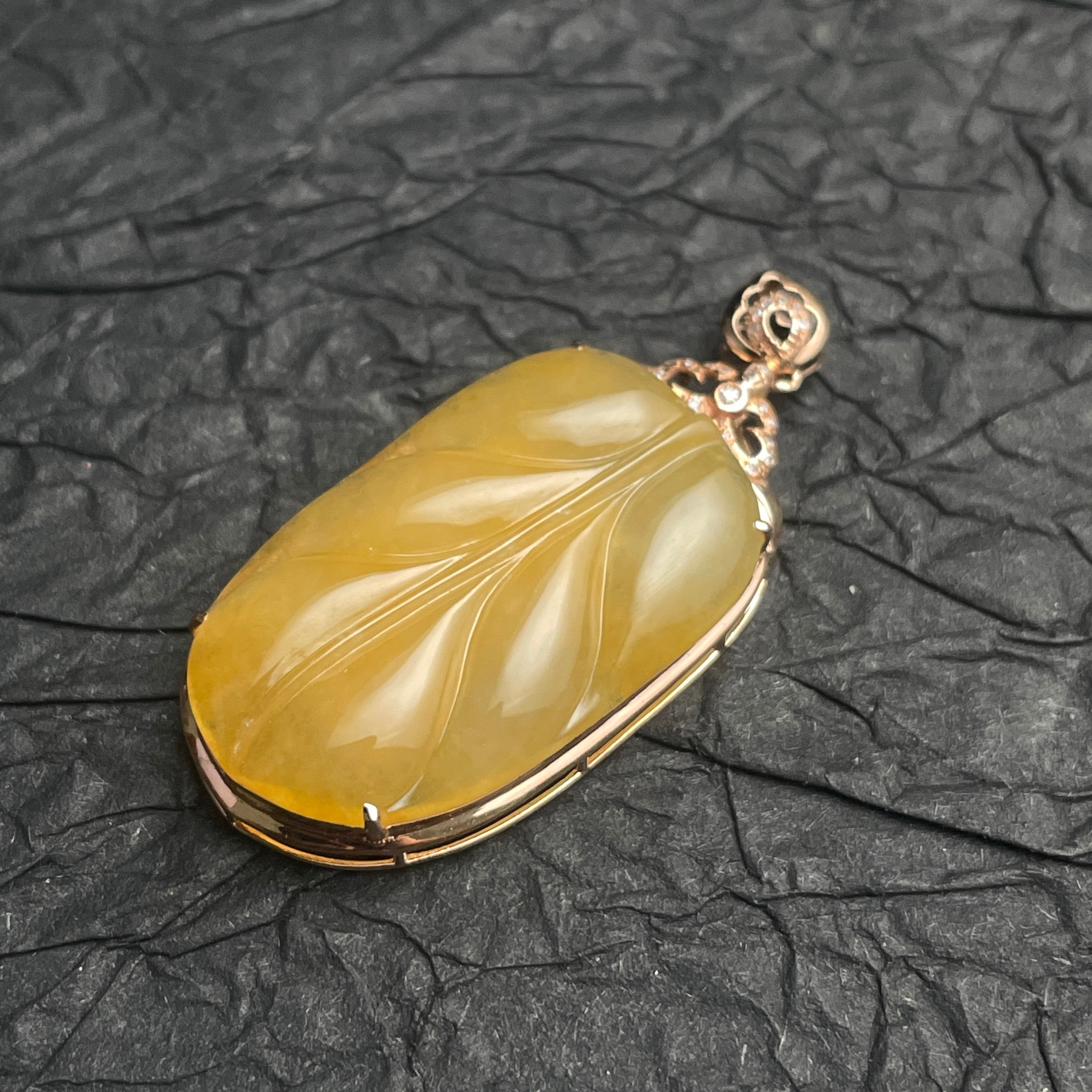 Sylvia Jewelry yellow jadeite leaf pendant carved in 18k rose gold with diamond accents on a black textured background