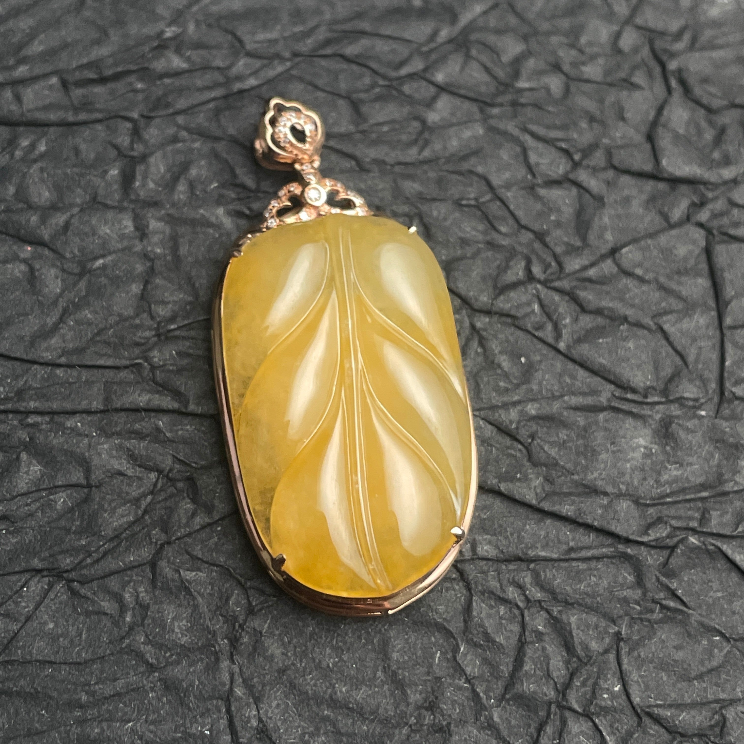 Sylvia Jewelry yellow jadeite leaf pendant carved in 18k rose gold with diamond accents on a dark textured background.